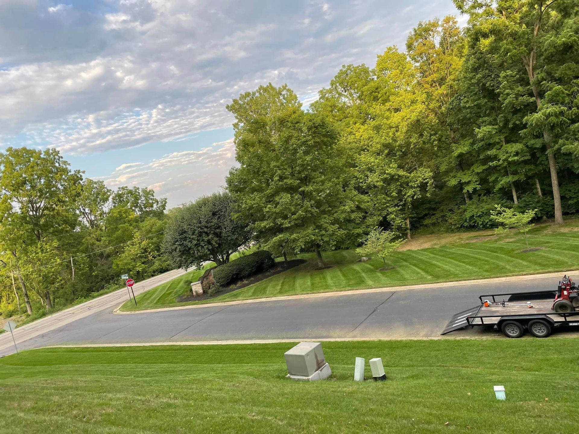 A lawn mower is sitting on top of a lush green lawn next to a road.