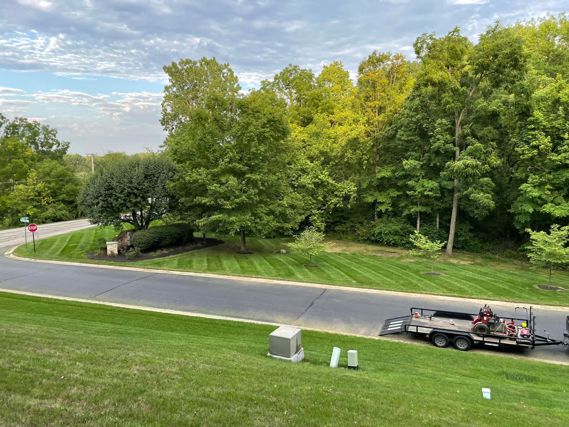 A truck is parked on the side of the road next to a lush green lawn.