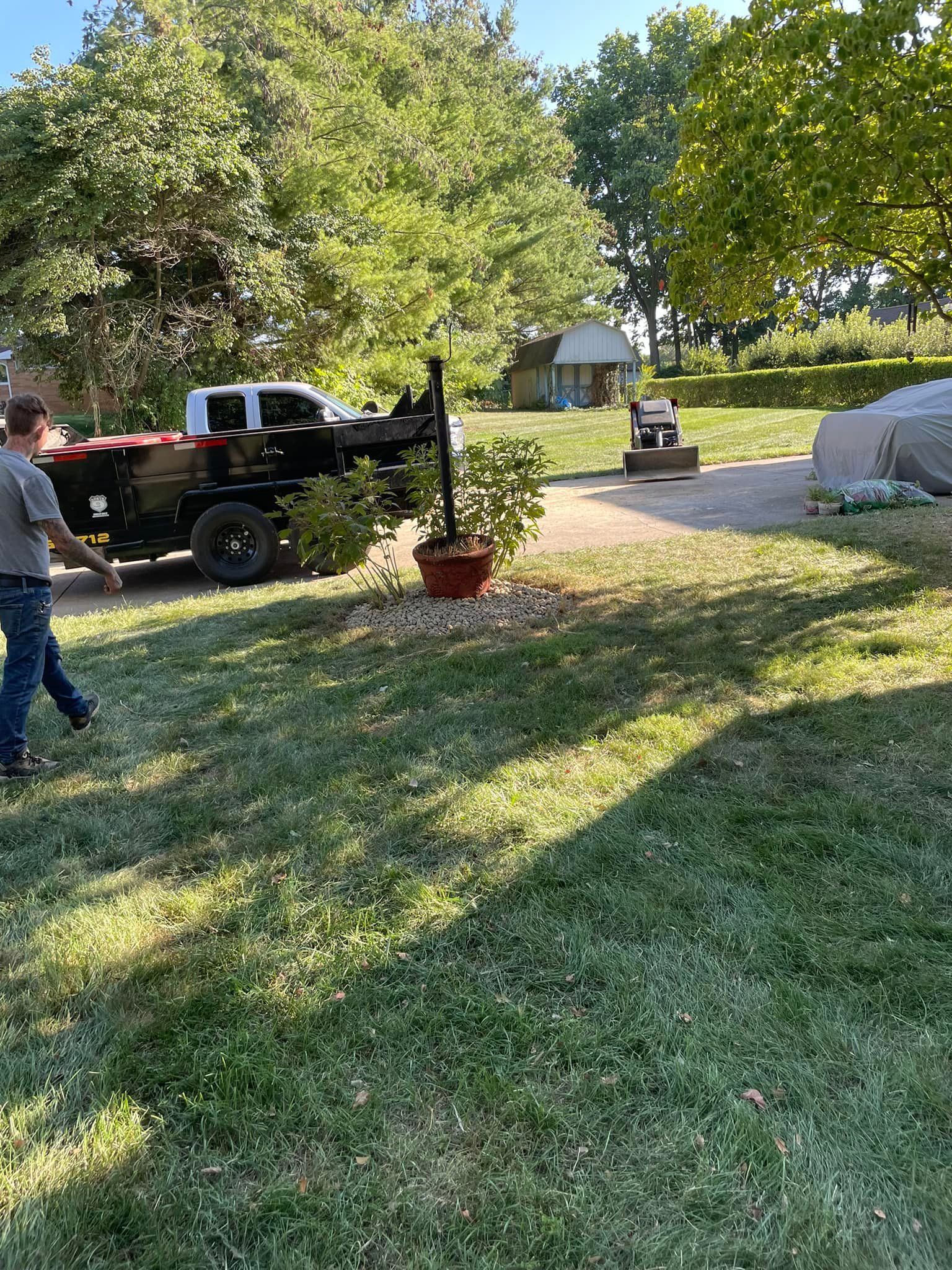 A man is walking in front of a truck in a yard.