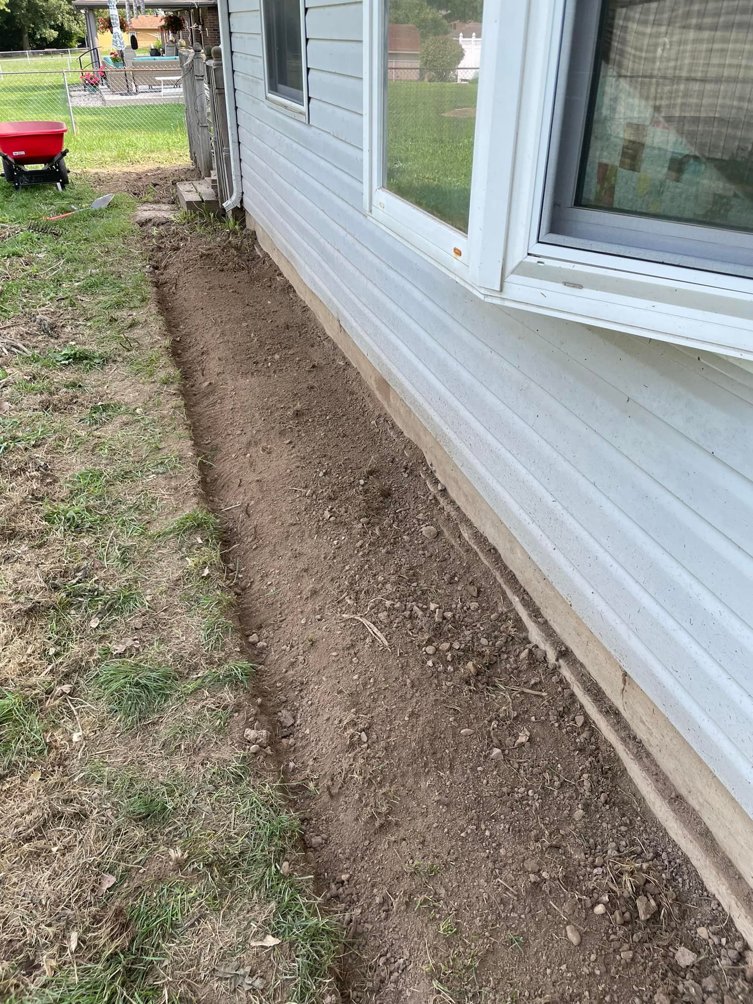 A white house with a red wheelbarrow in front of it.