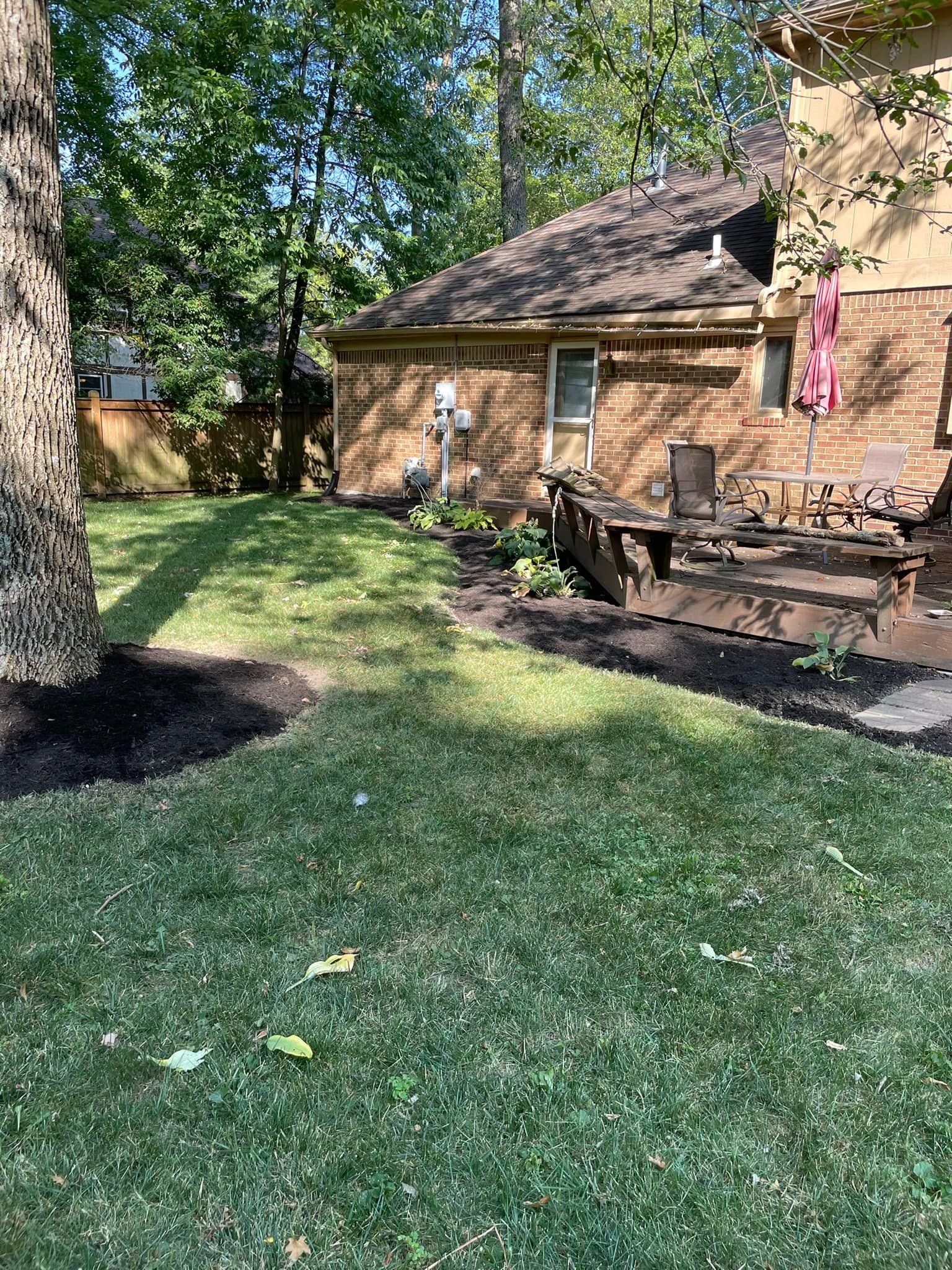 A backyard of a house with a lush green lawn and a deck.