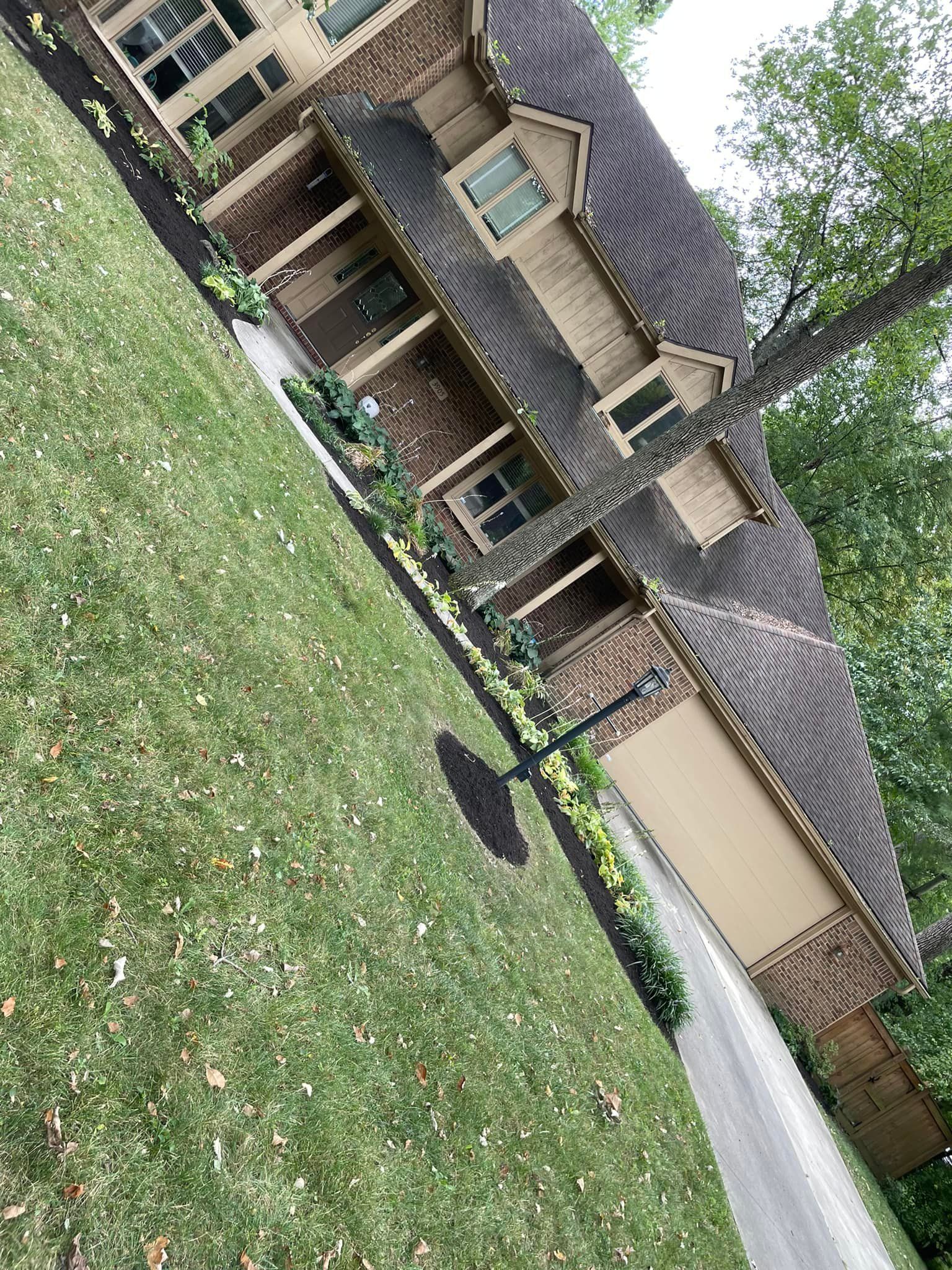 A large brick house with a driveway and a large lawn in front of it.