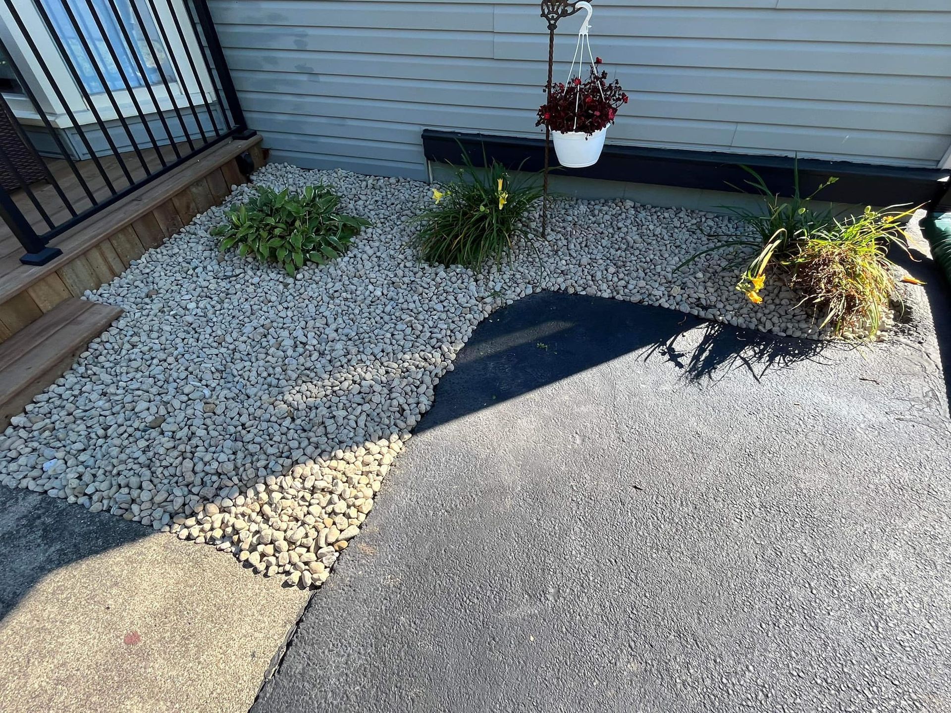 There is a hanging potted plant in the middle of the gravel.