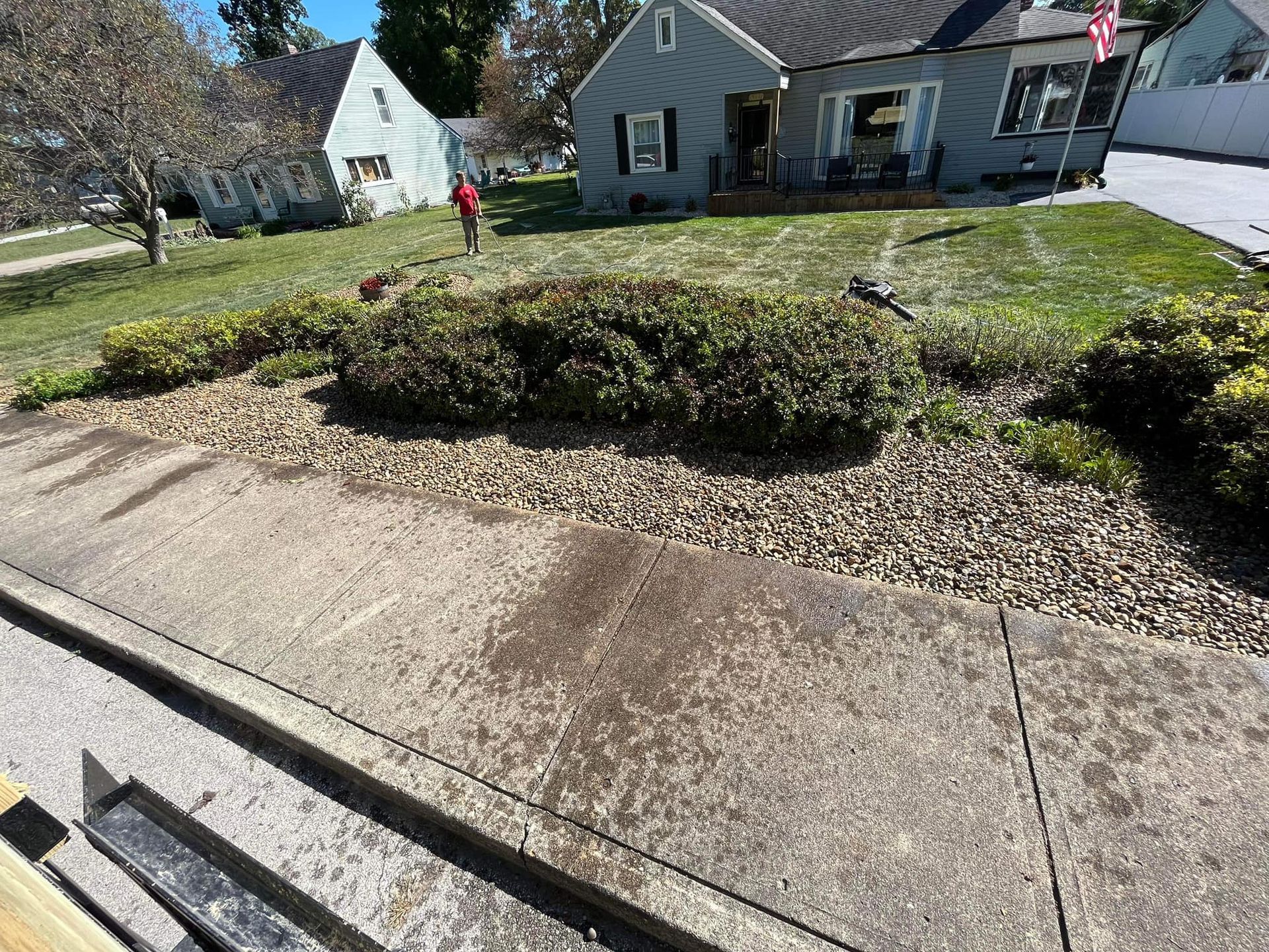 A person is standing on a sidewalk in front of a house.