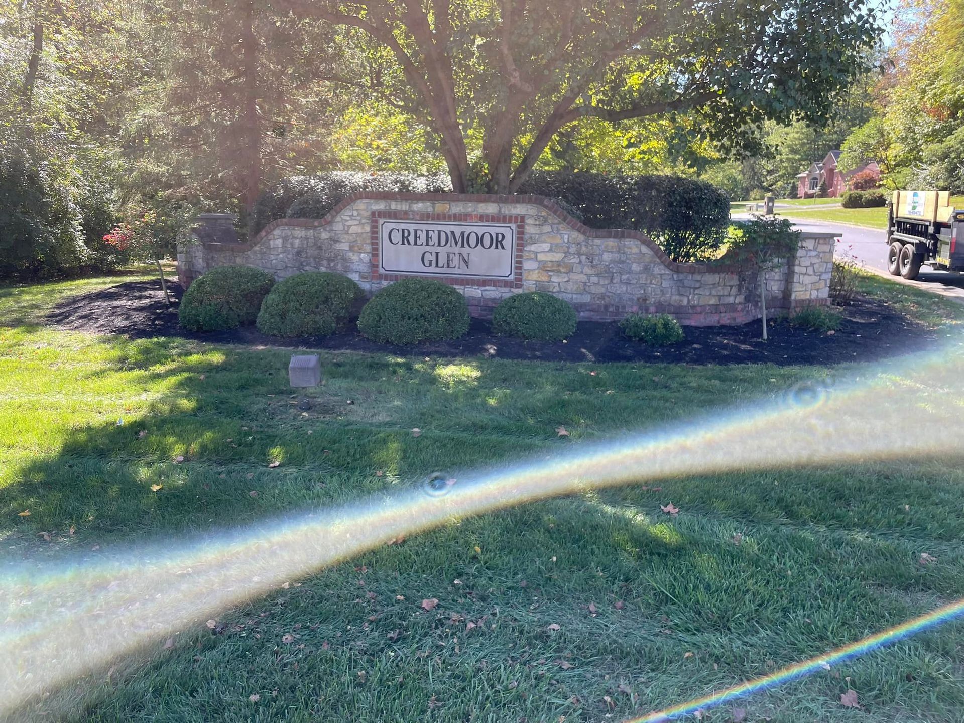 A large stone sign in the middle of a lush green field.