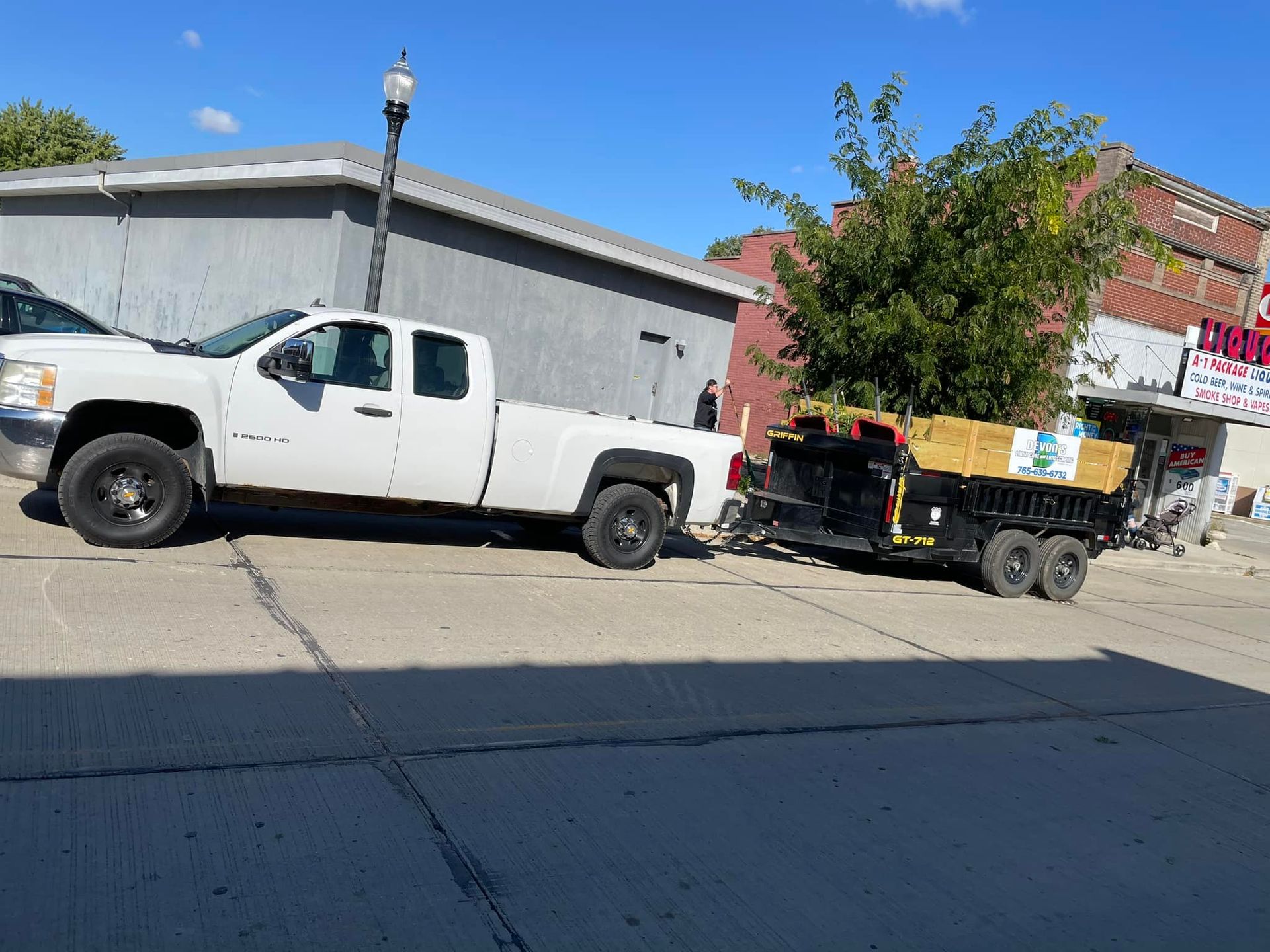 A white truck with a trailer attached to it is parked on the side of the road.