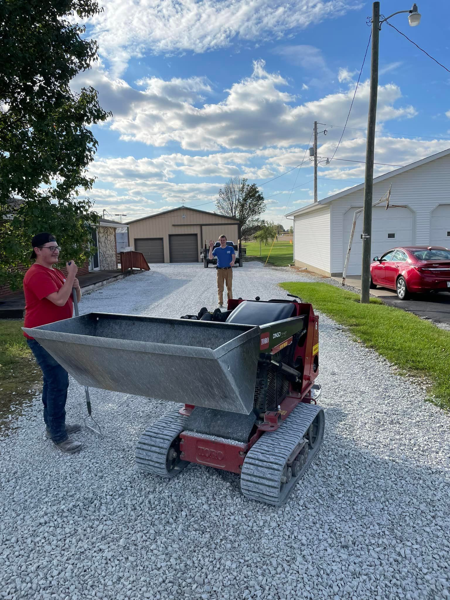 A man is standing next to a dump truck on a gravel road.