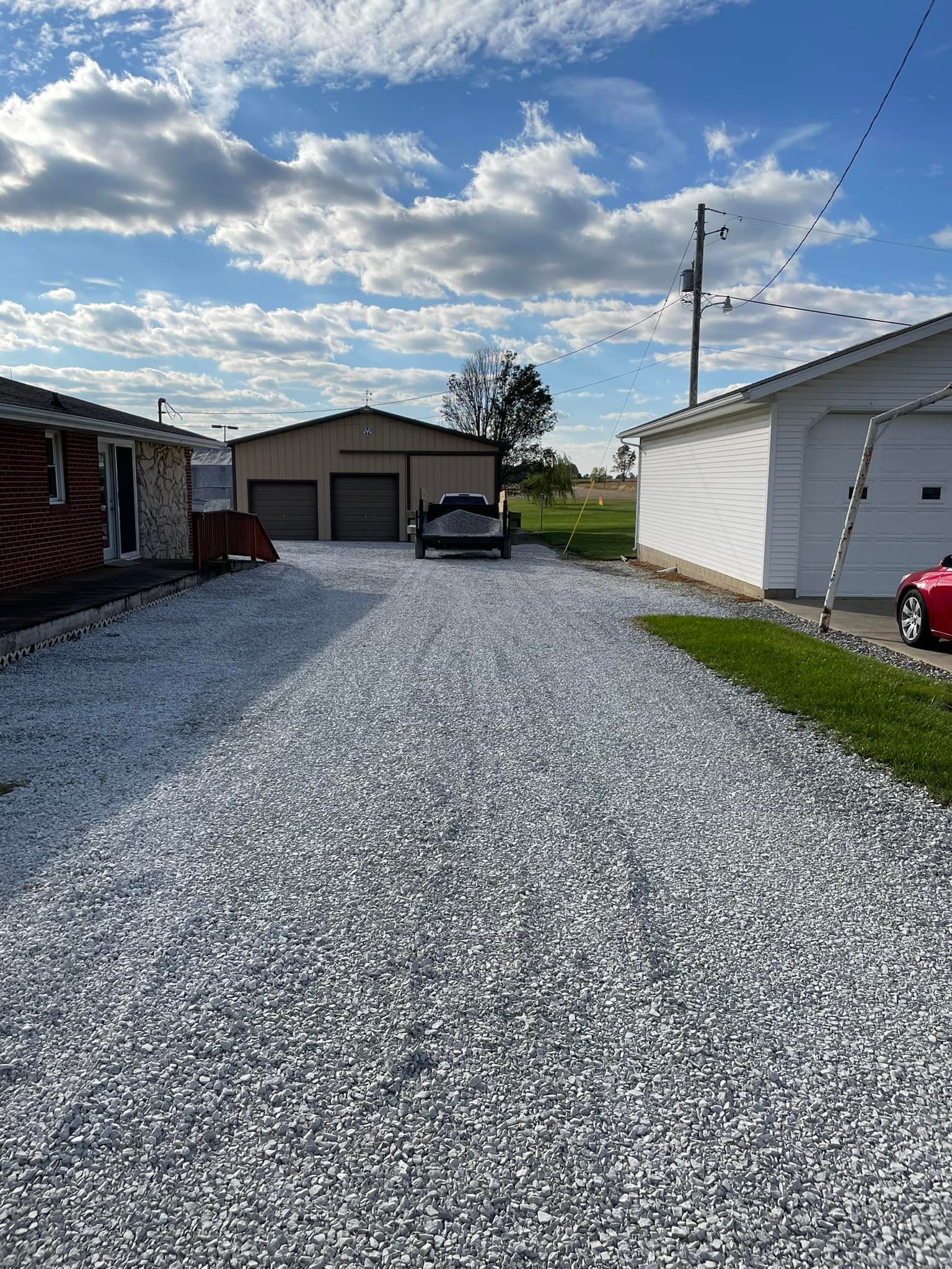 A car is parked on the side of a gravel road.
