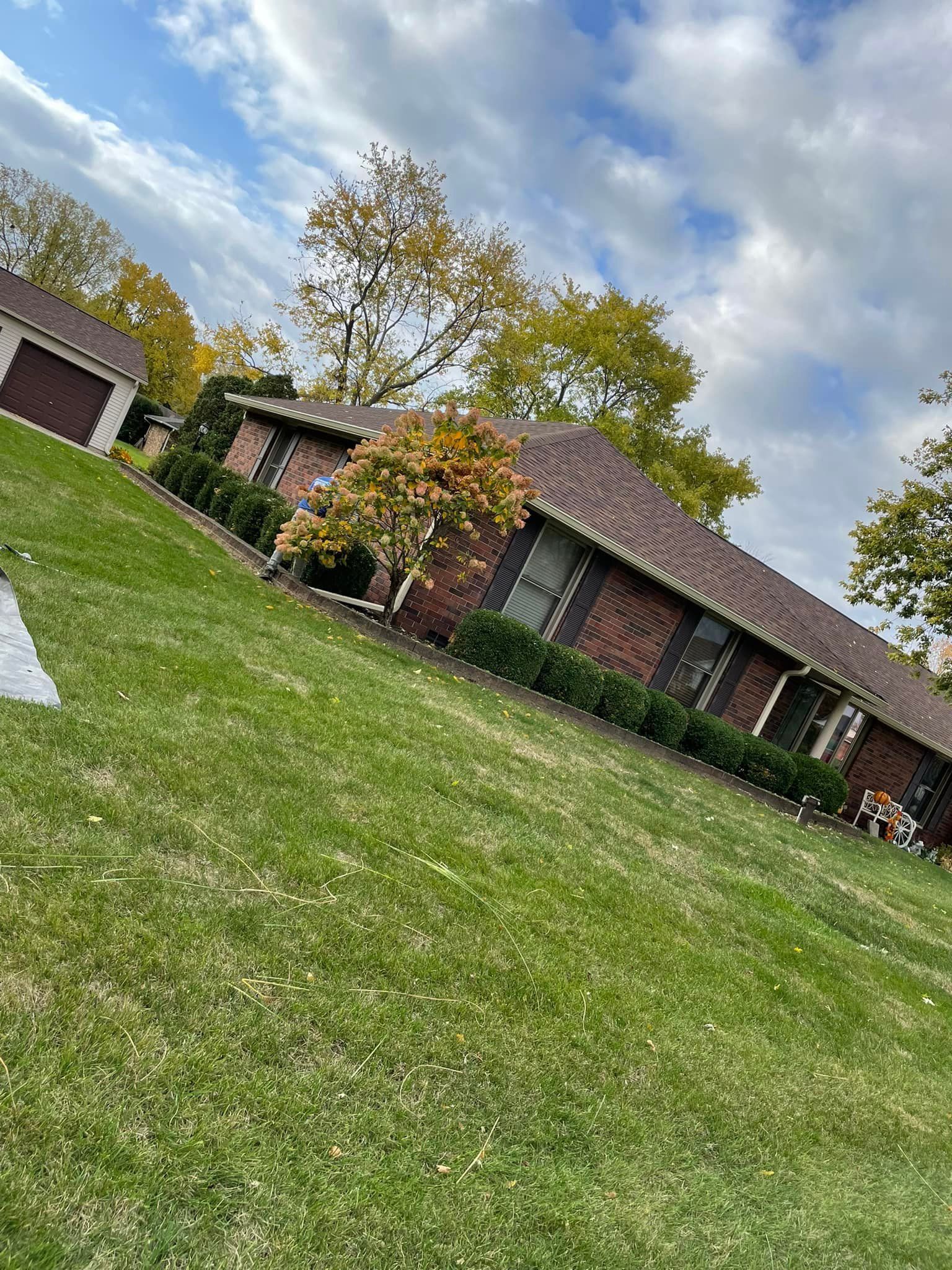 A brick house with a large lawn in front of it.