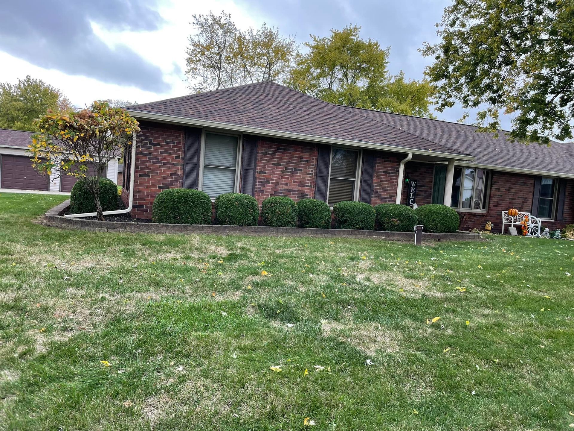 A brick house with a large lawn in front of it.