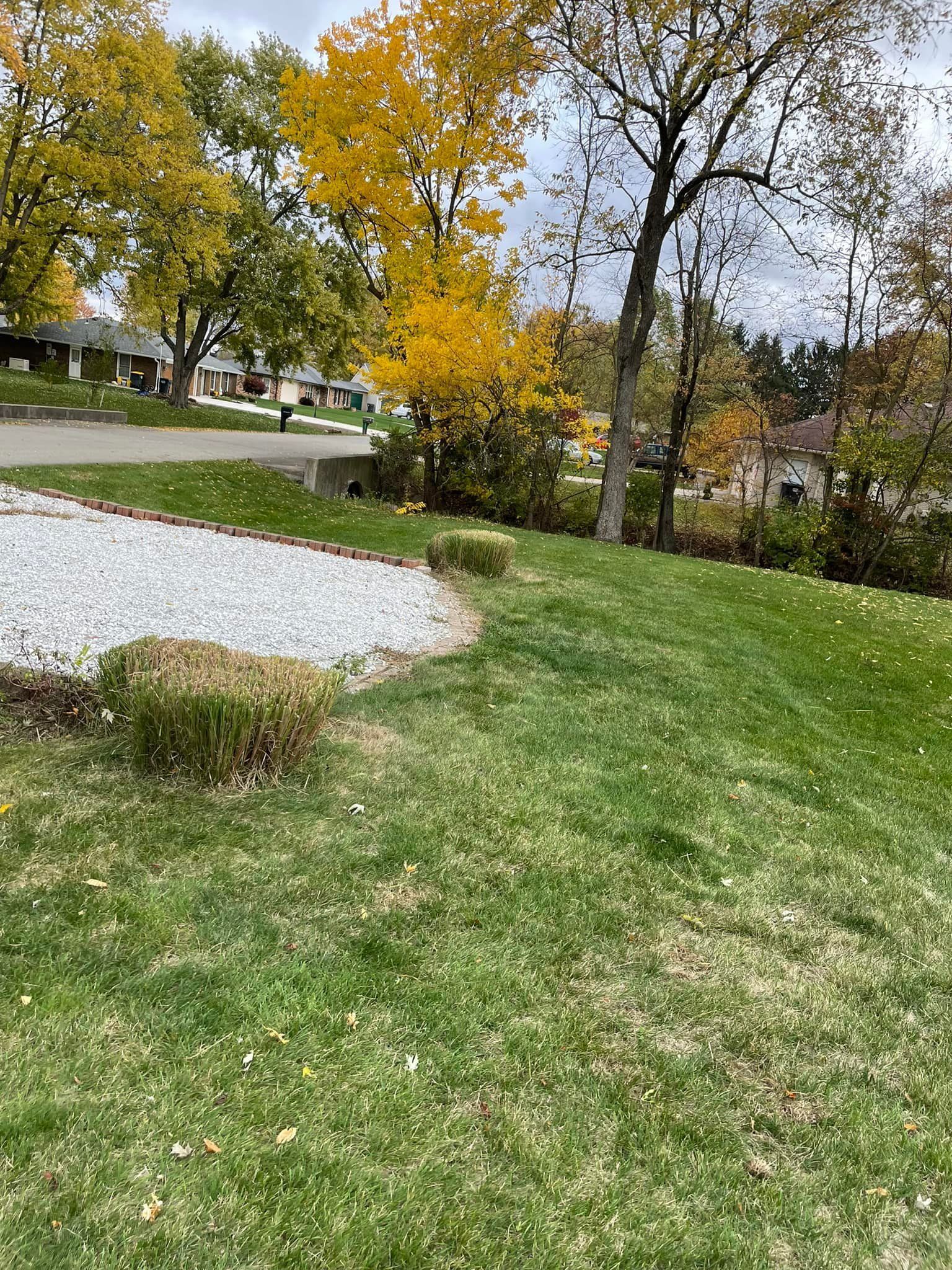 A lush green lawn with trees in the background and hay bales in the foreground.