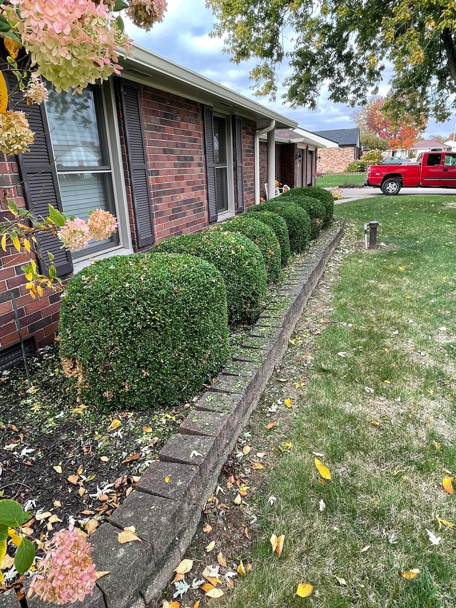 A red truck is parked in front of a brick house.