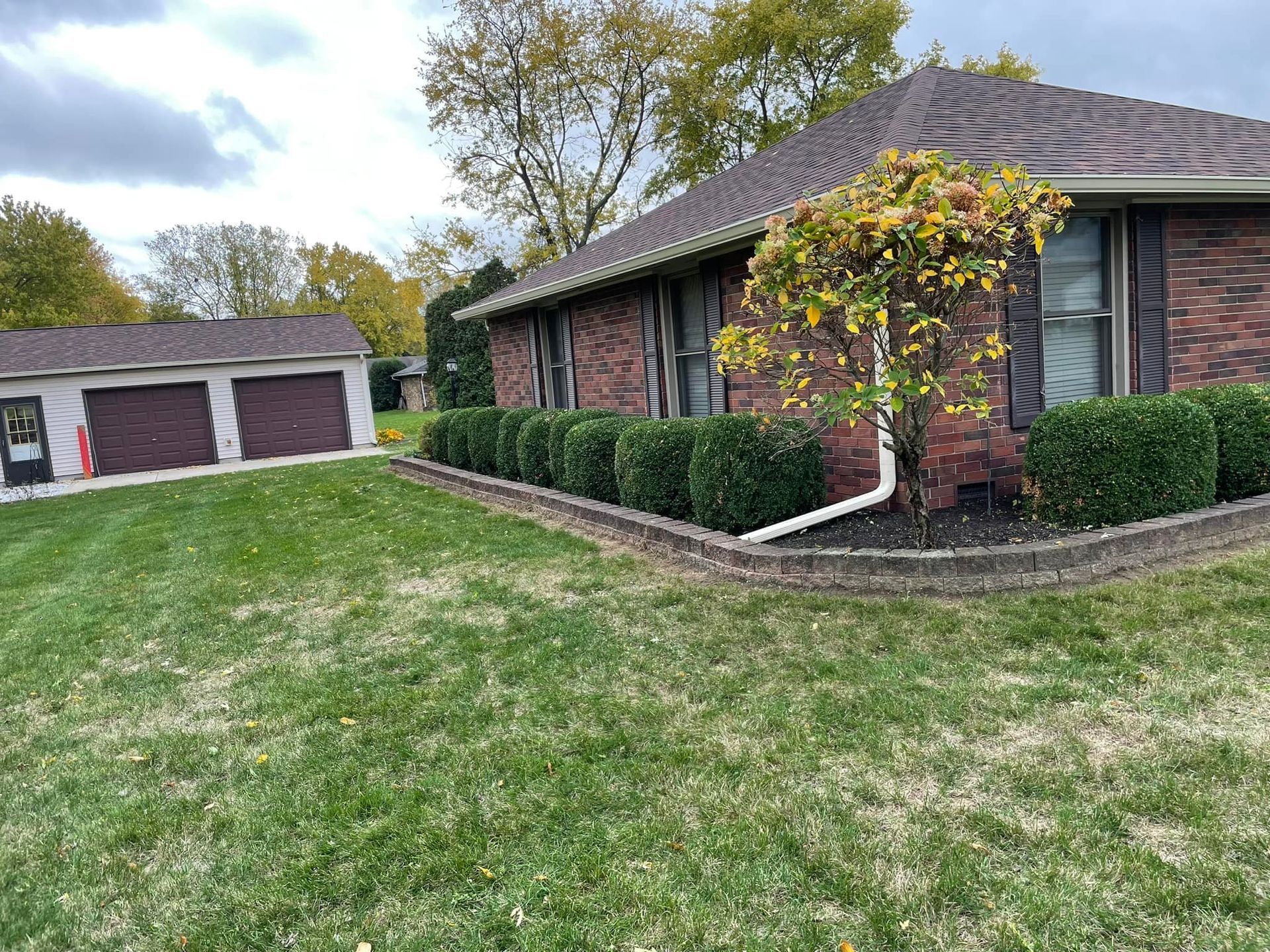 A brick house with a lush green lawn in front of it.