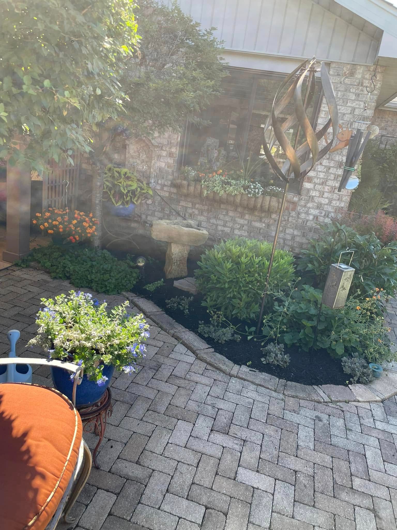 A brick patio with a couch and chairs in front of a house.