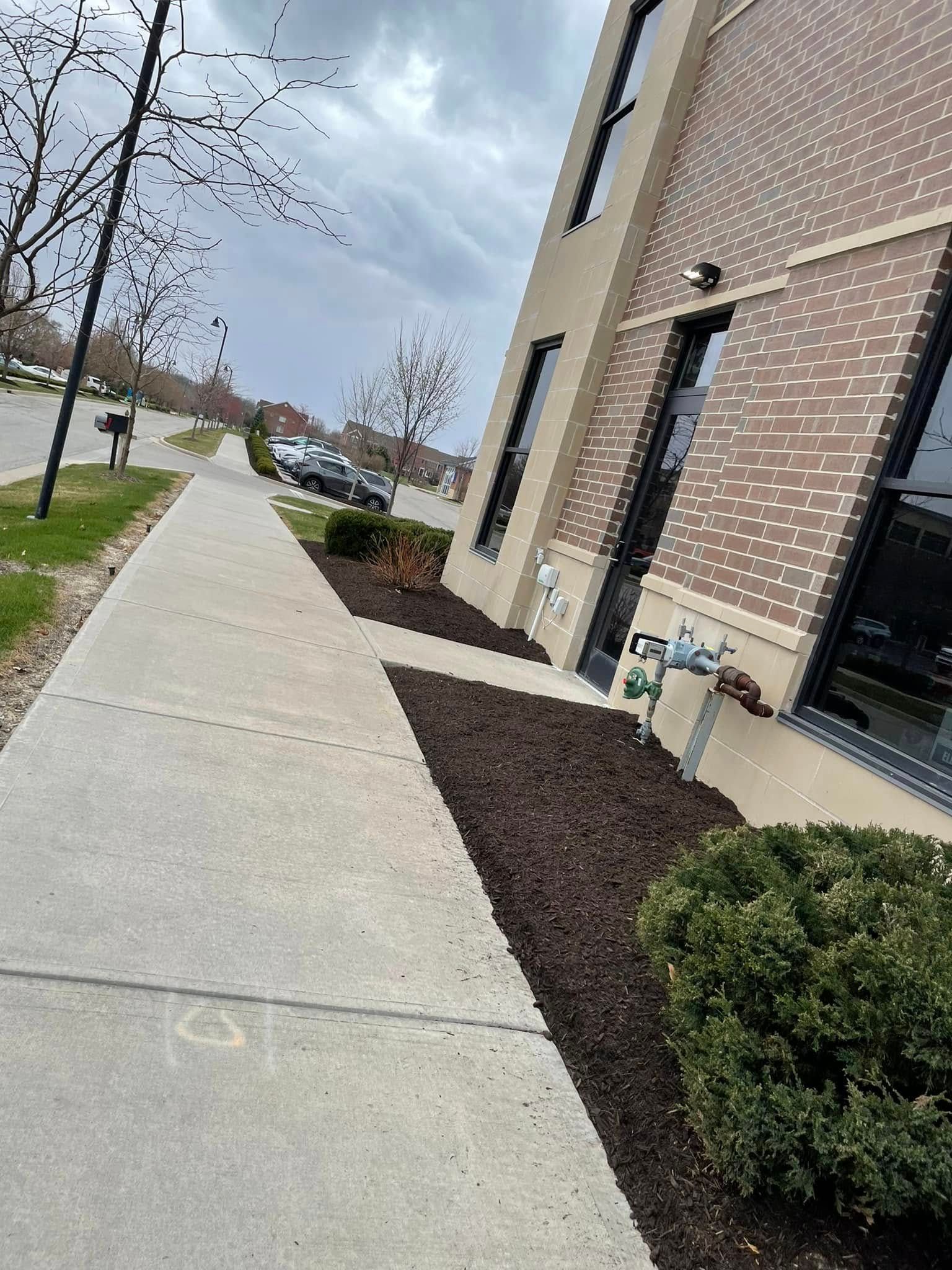 A sidewalk in front of a brick building with a handicapped sign on it