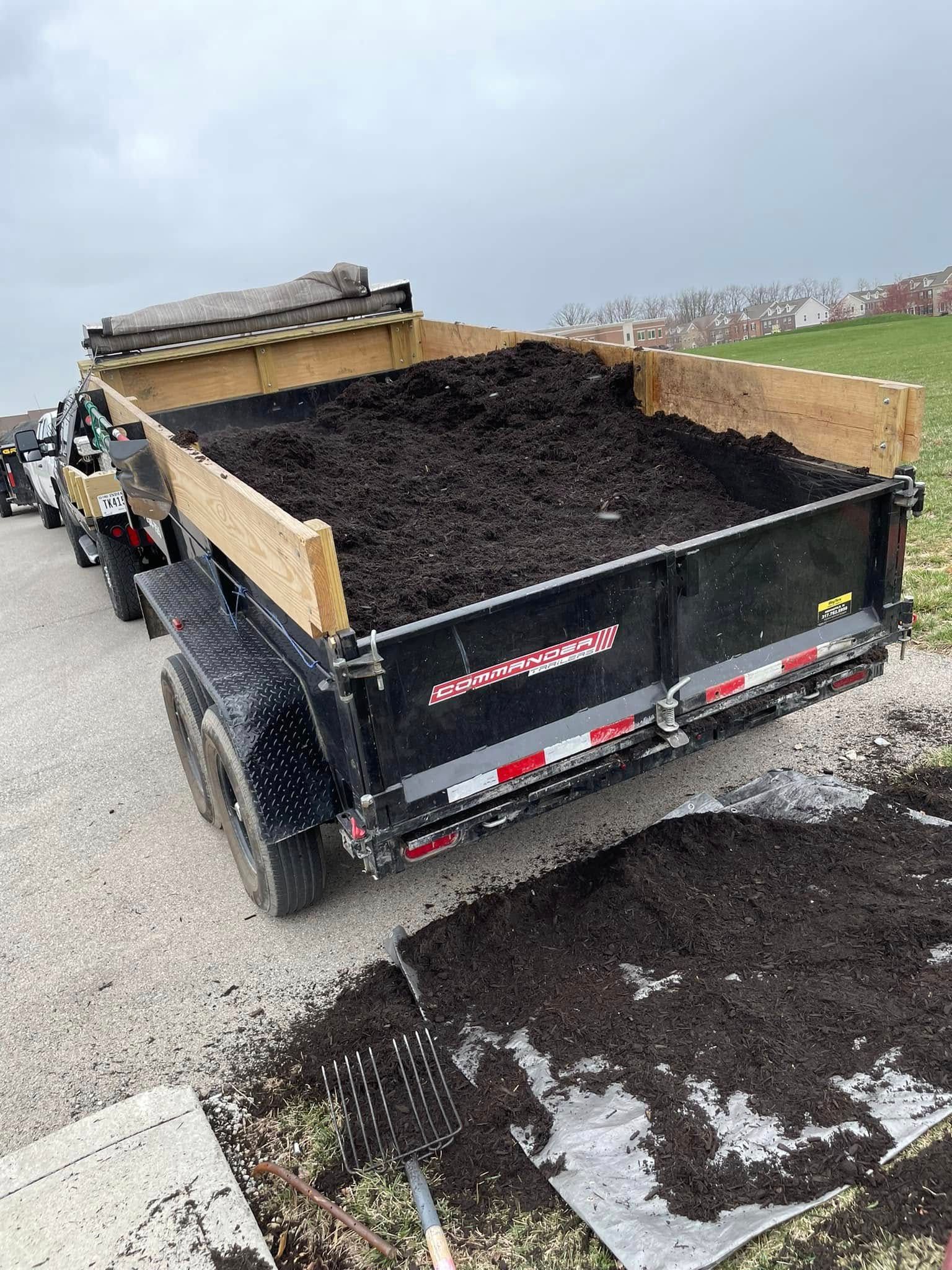 A dump truck filled with dirt is parked on the side of the road.