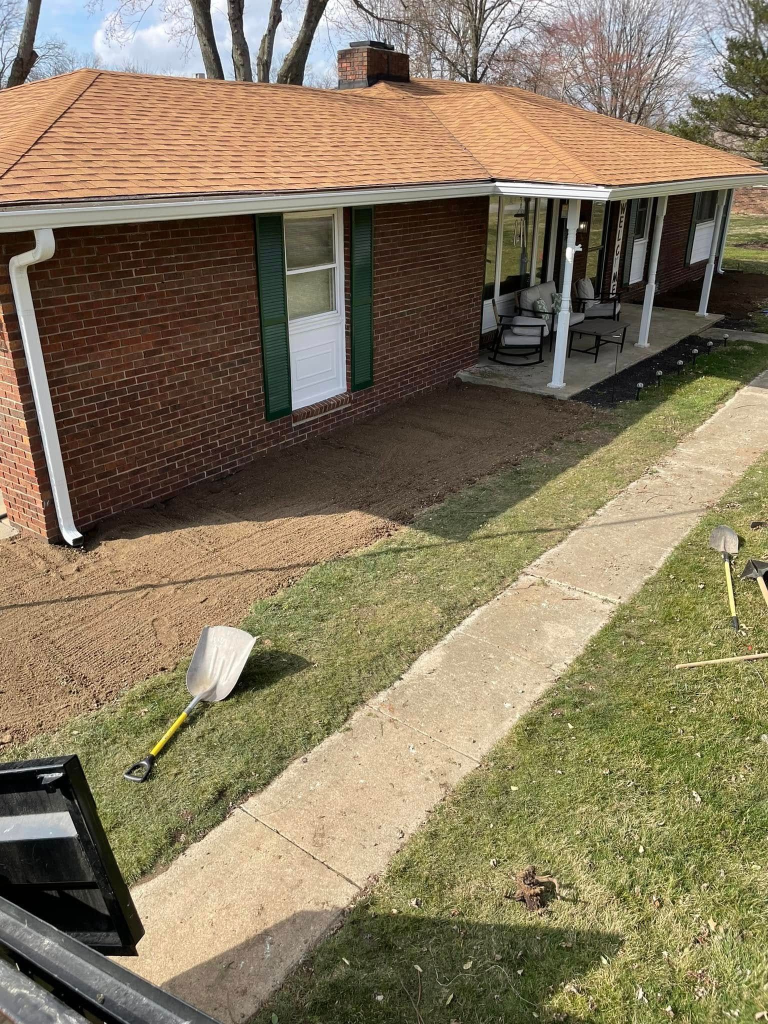 A brick house with a porch and a shovel in front of it.