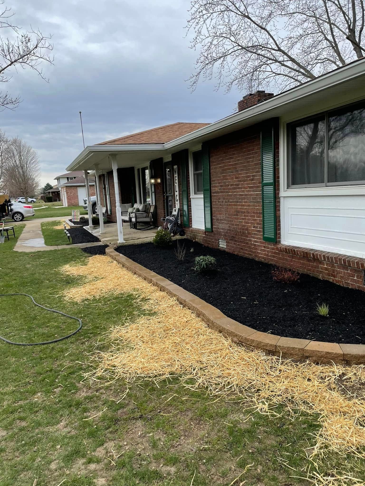 A brick house with a black mulch bed in front of it.