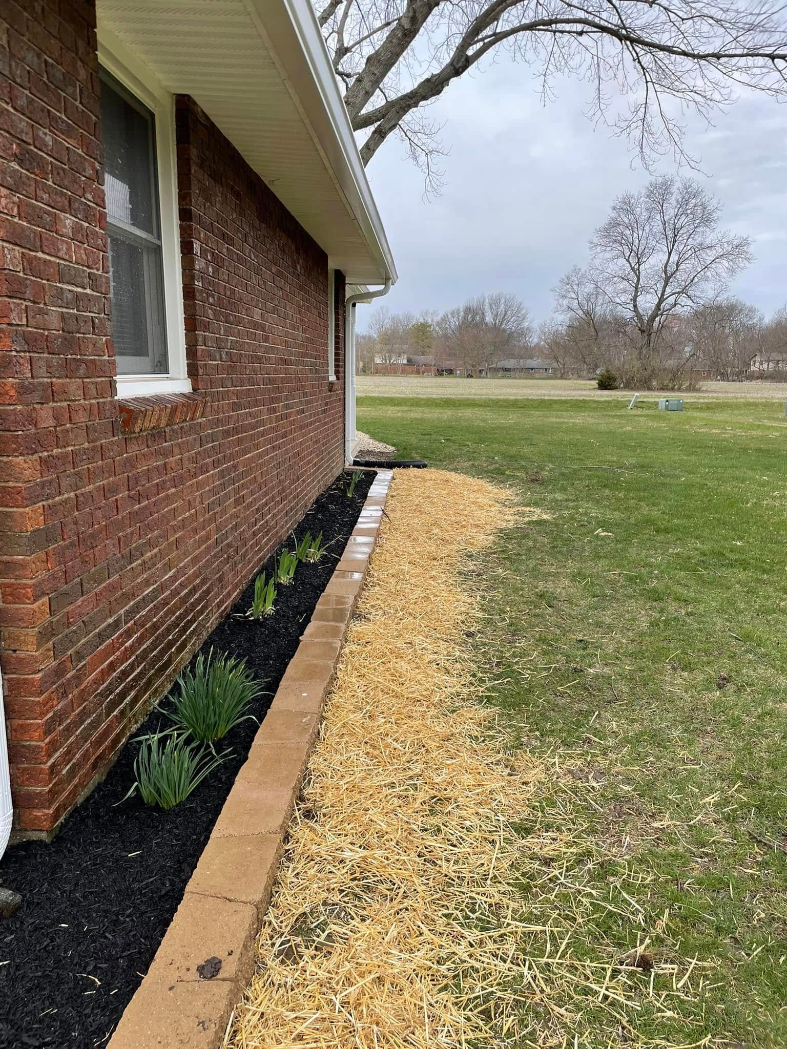 A brick house with a lush green yard in front of it.