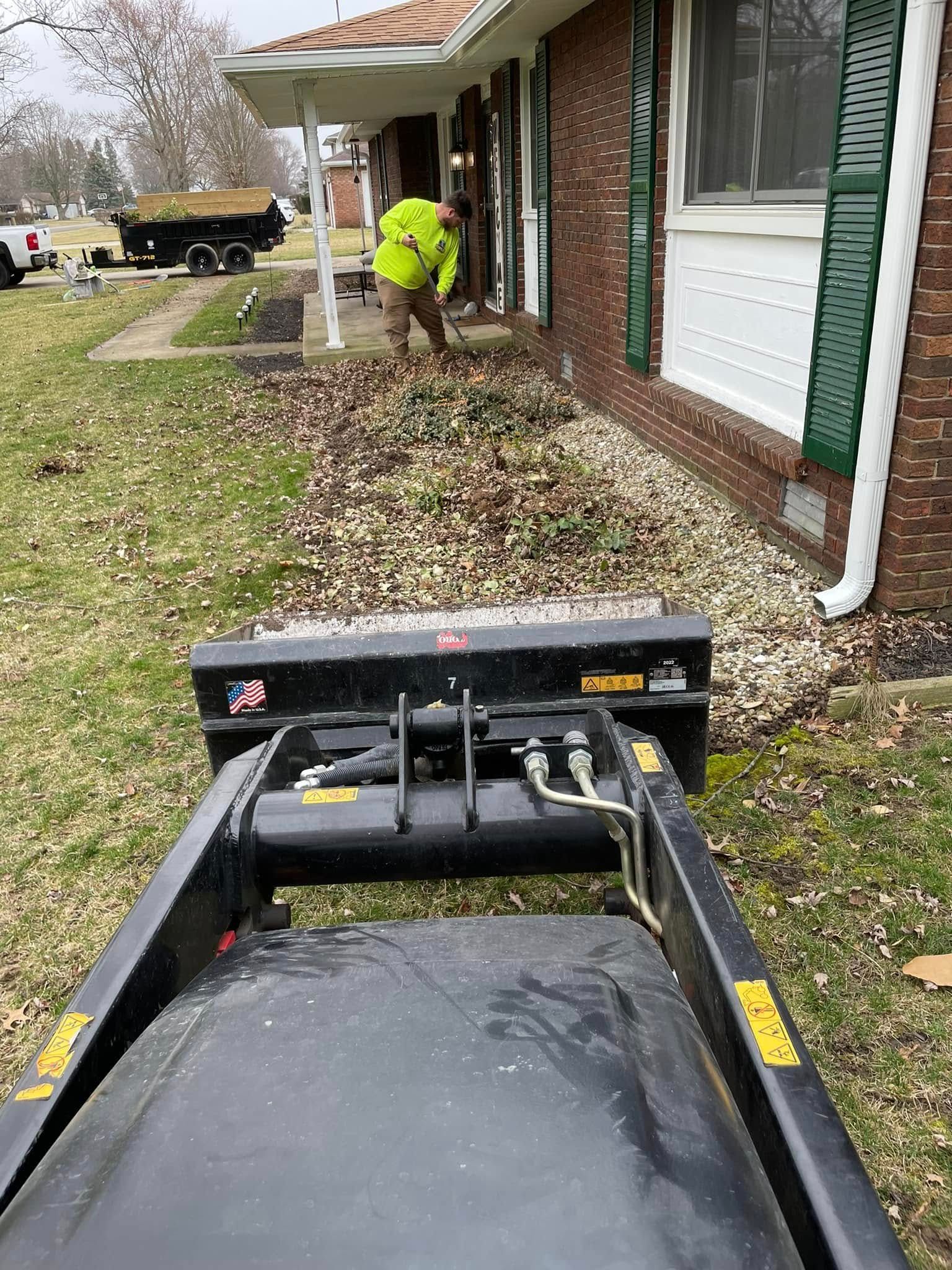 A man is standing next to a dumpster in front of a house.
