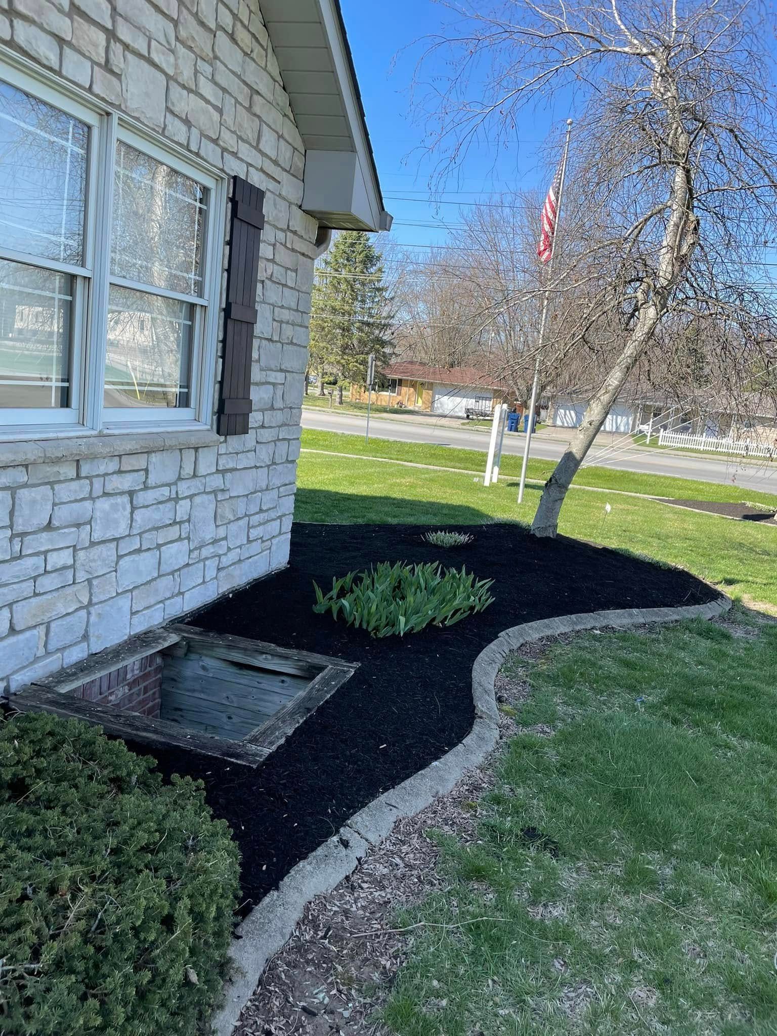 A brick house with a black mulch border in front of it.