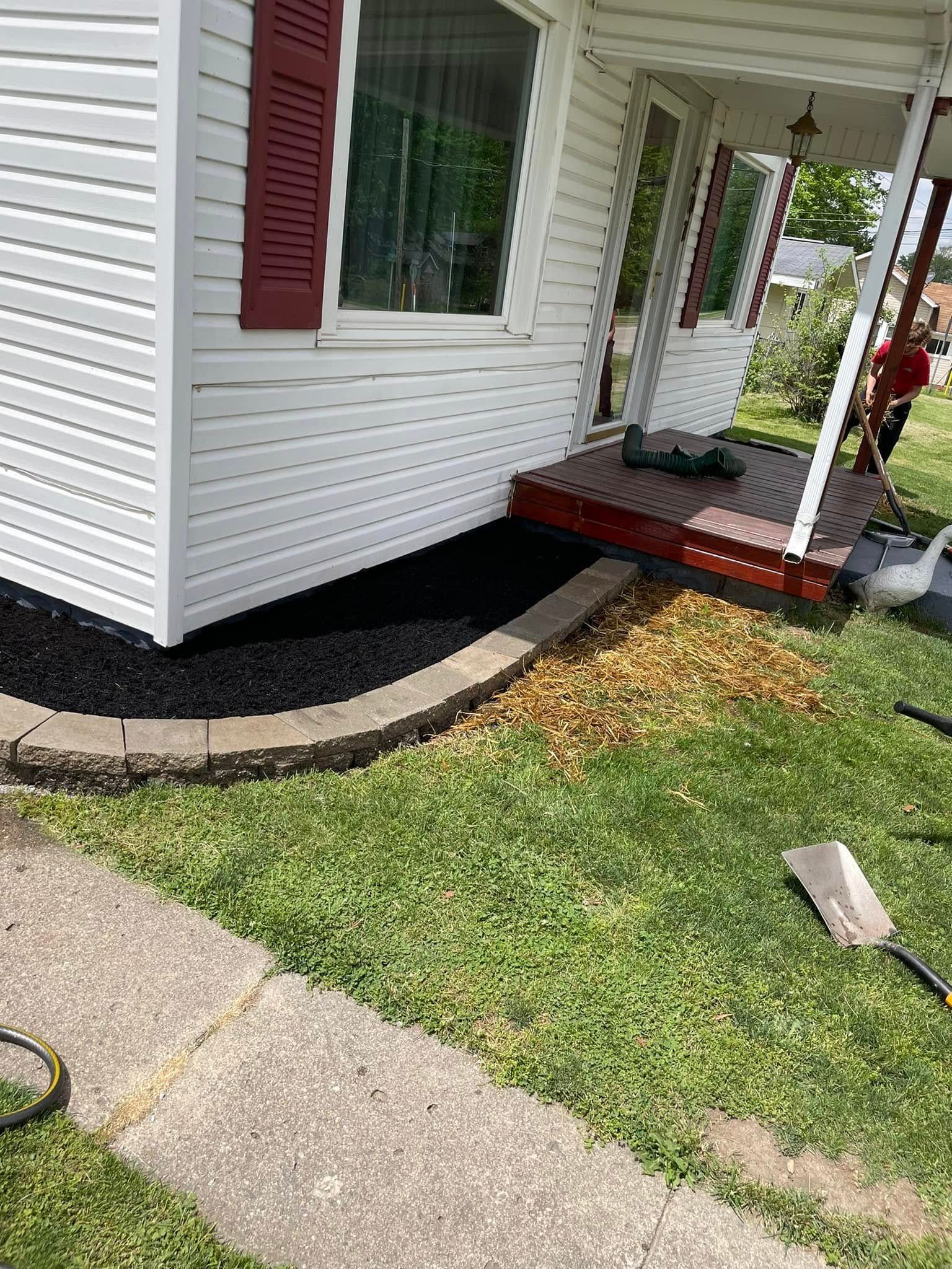 A man is working on the sidewalk in front of a house.