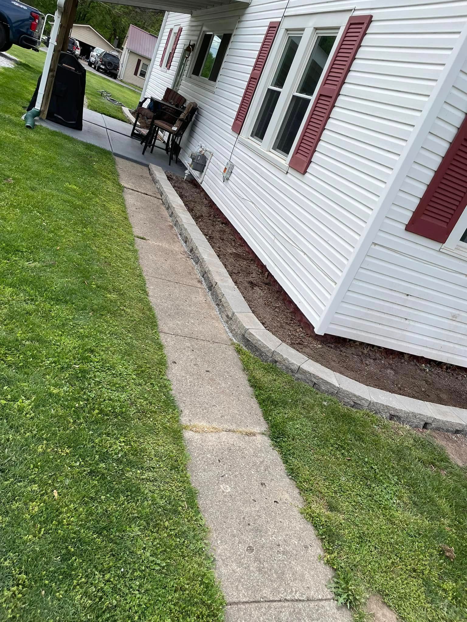 A sidewalk leading to a white house with red shutters.