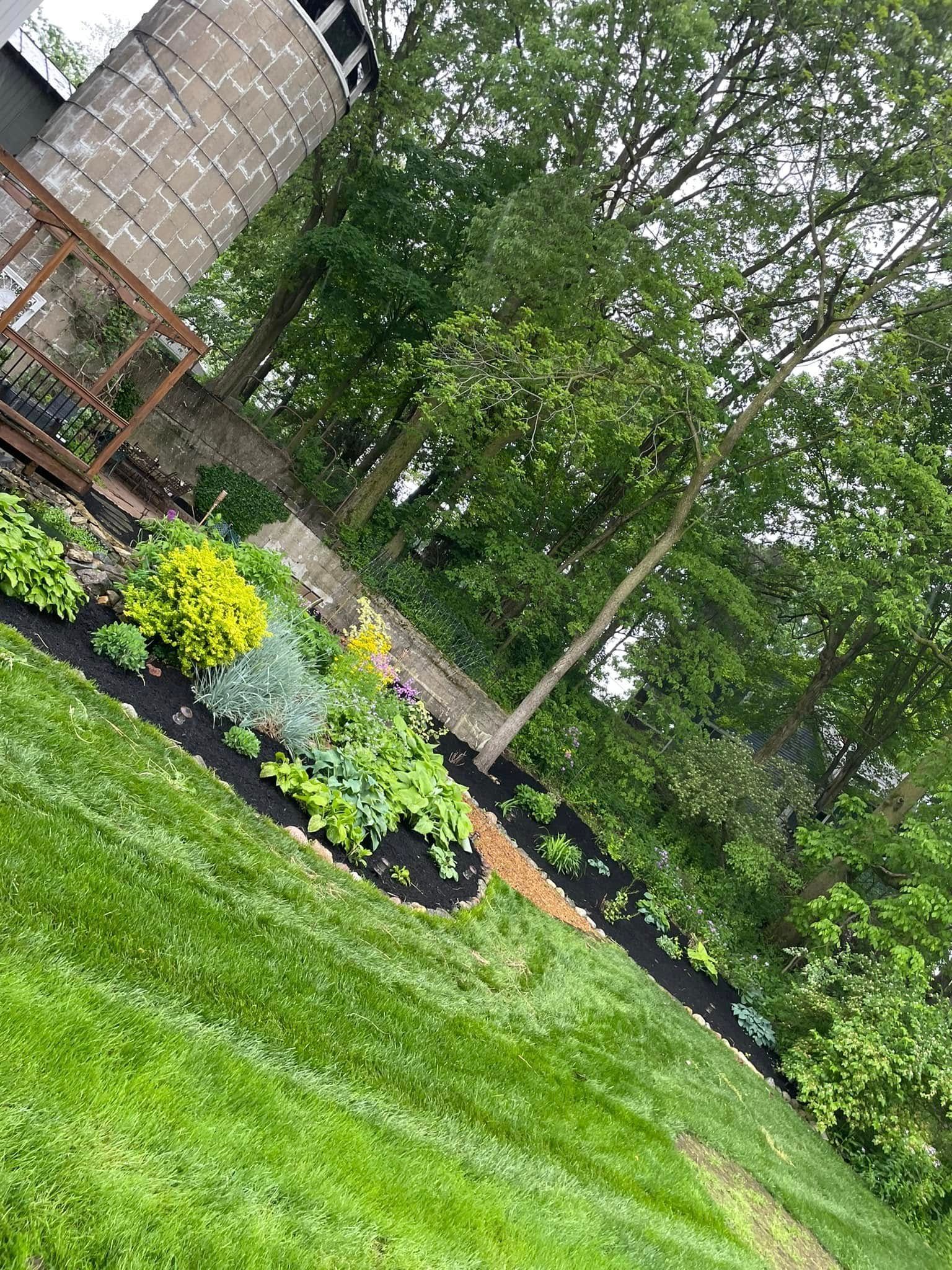 A lush green lawn with a deck and trees in the background.