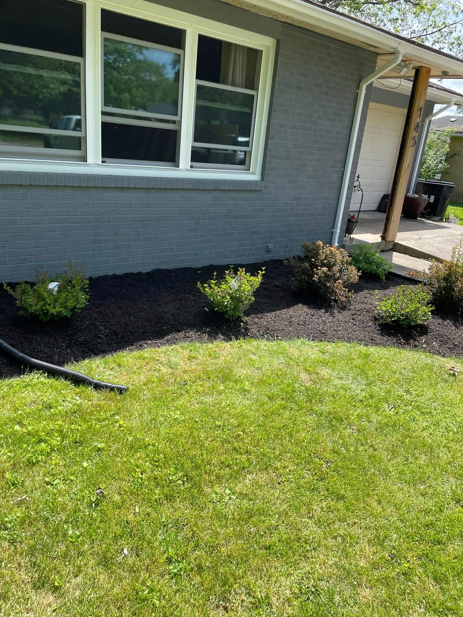 A gray house with a lush green lawn in front of it.