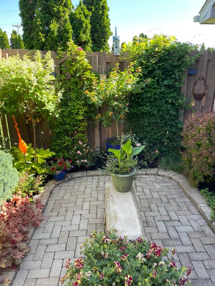 A brick patio with a bench and potted plants in a garden.