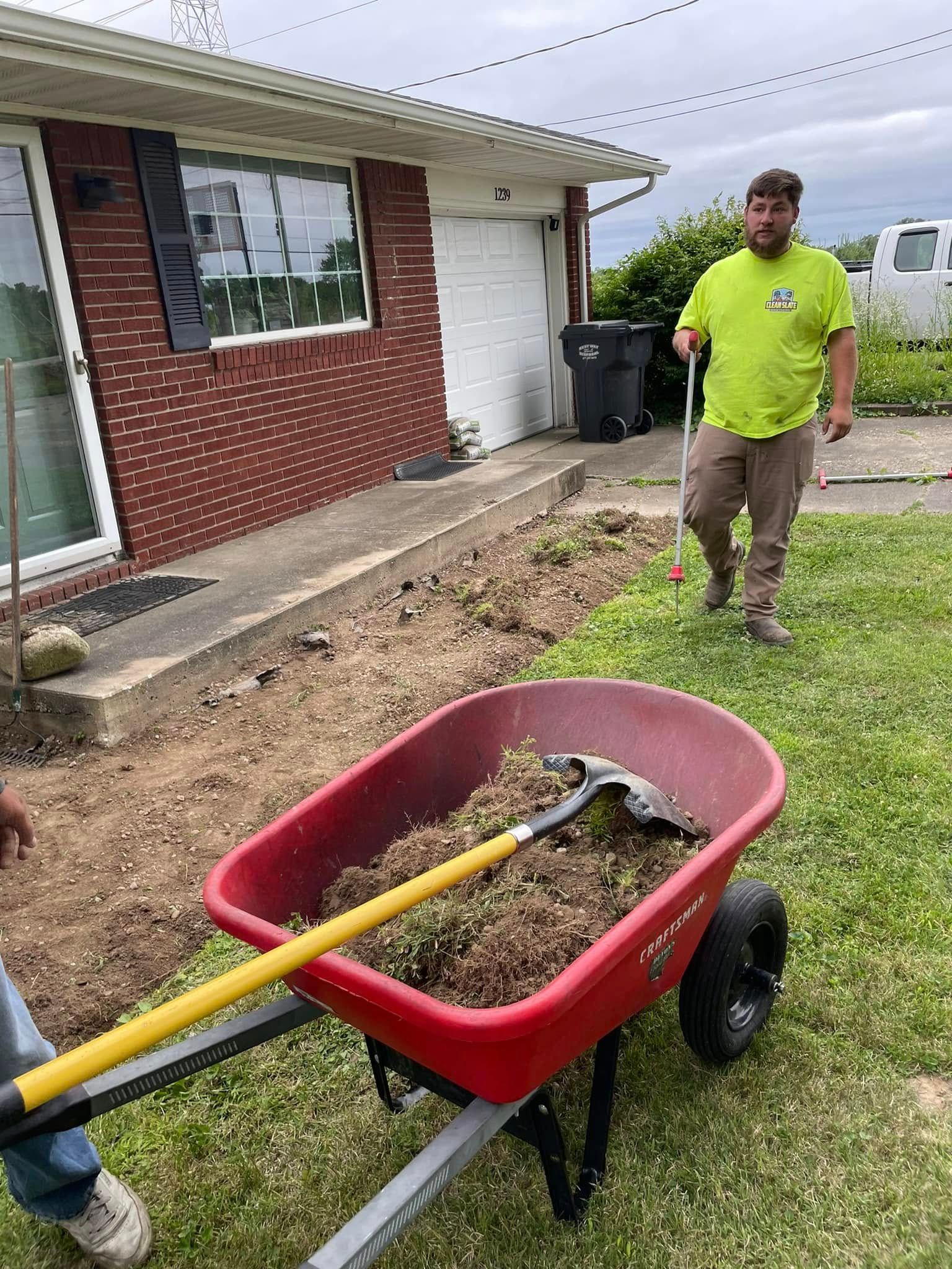 A man is pushing a wheelbarrow full of dirt in front of a house.