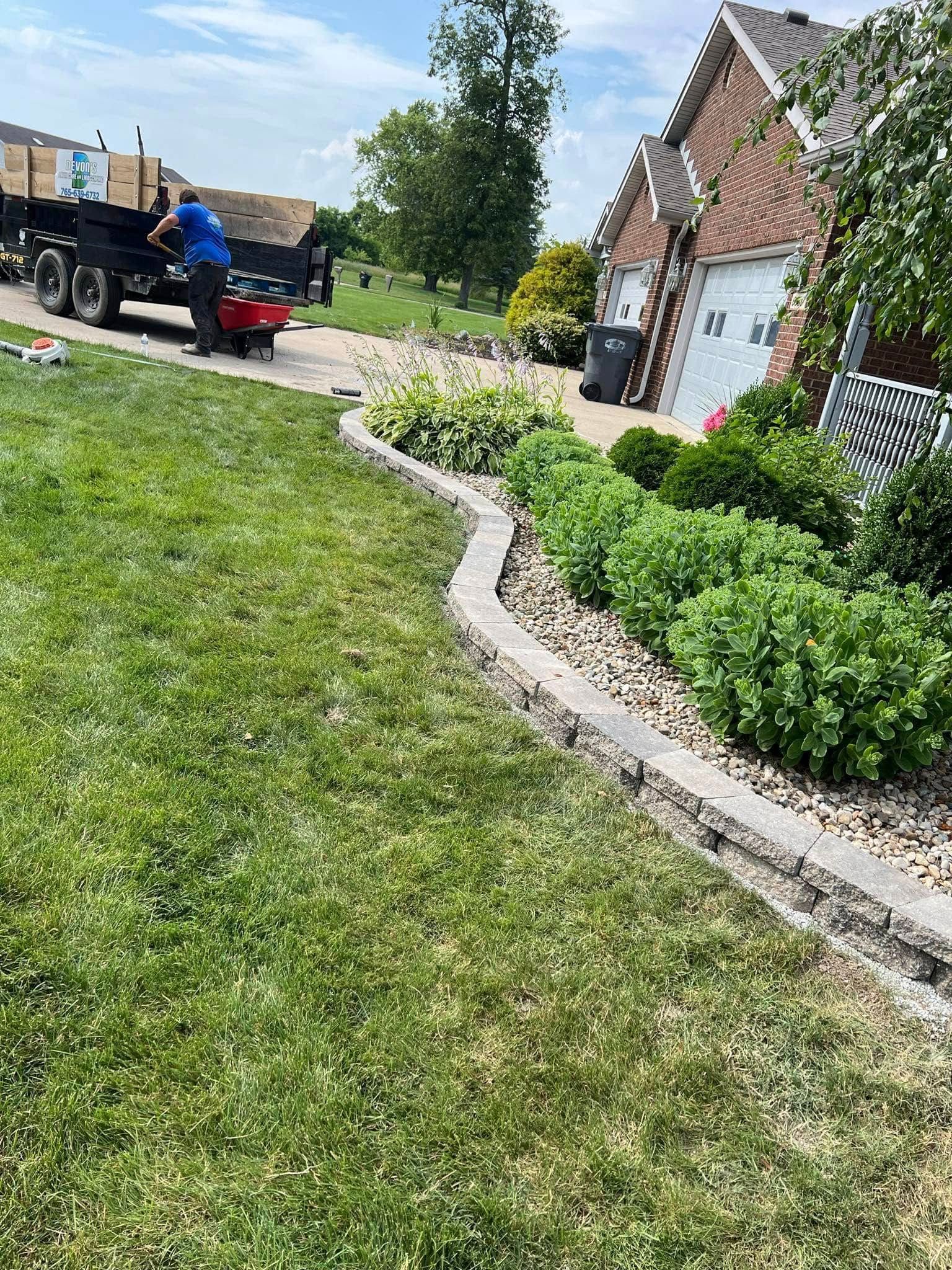 A man is riding a lawn mower in front of a house.