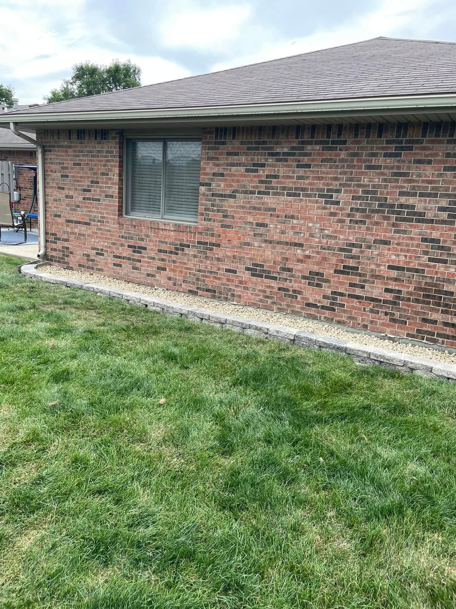A brick house with a large lawn in front of it.