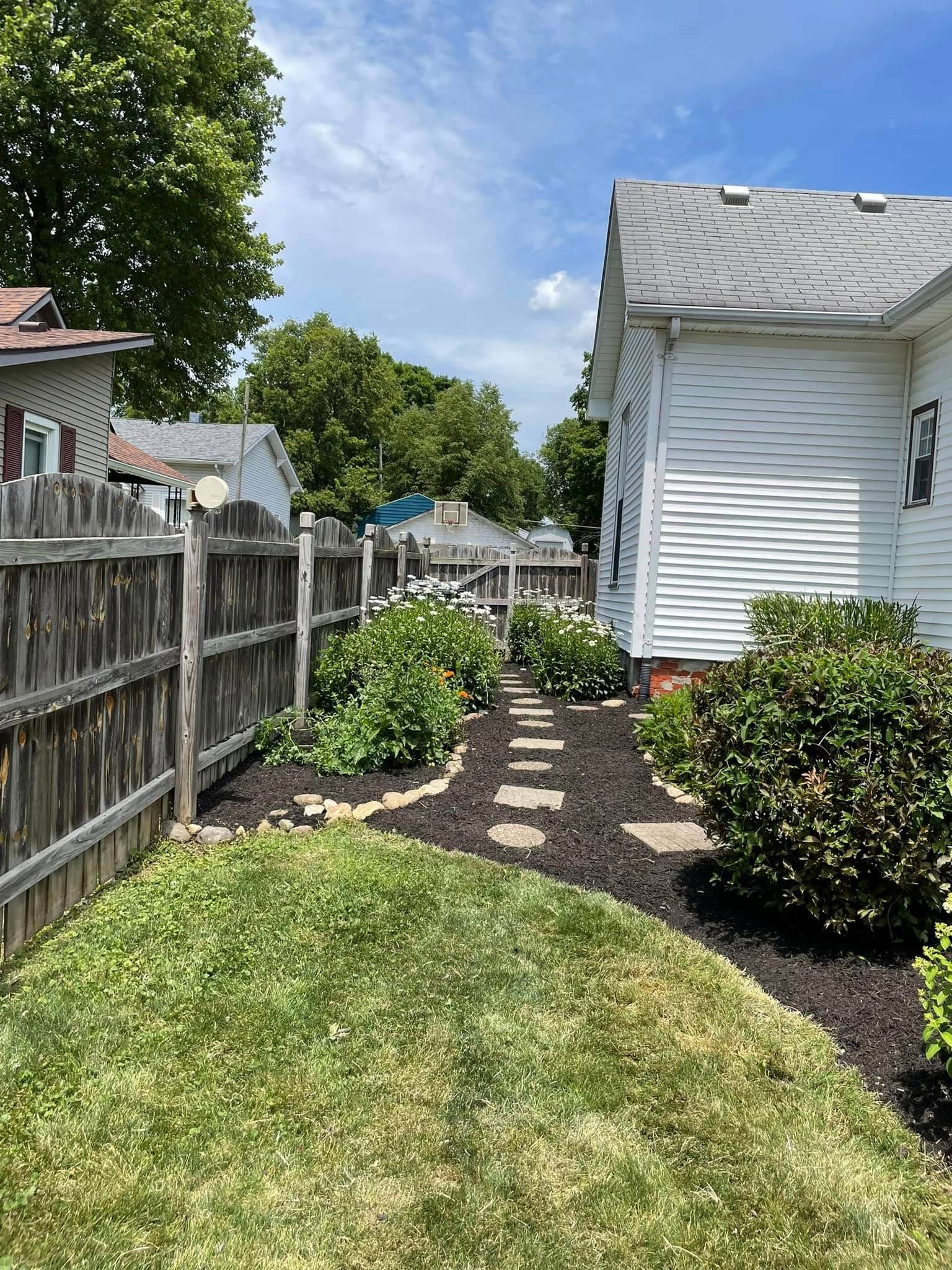 A backyard with a fence and a path leading to a house.