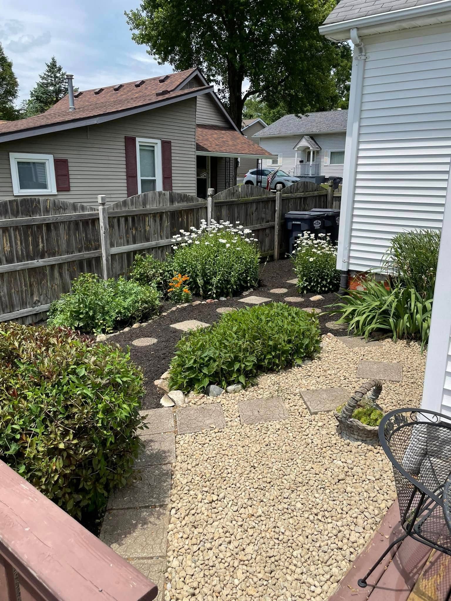 A yard with a fence and a table and chairs in front of a house.