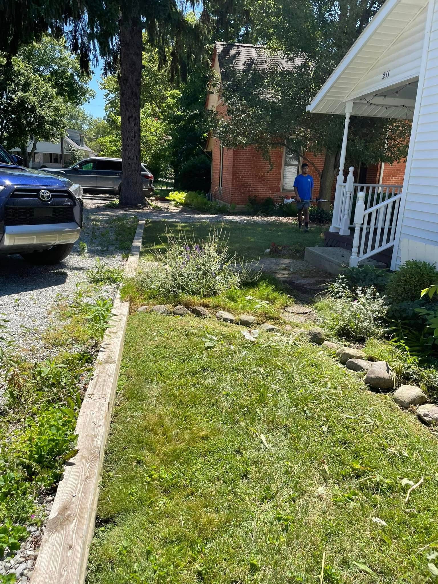 A man is standing in front of a house with a car parked in front of it.
