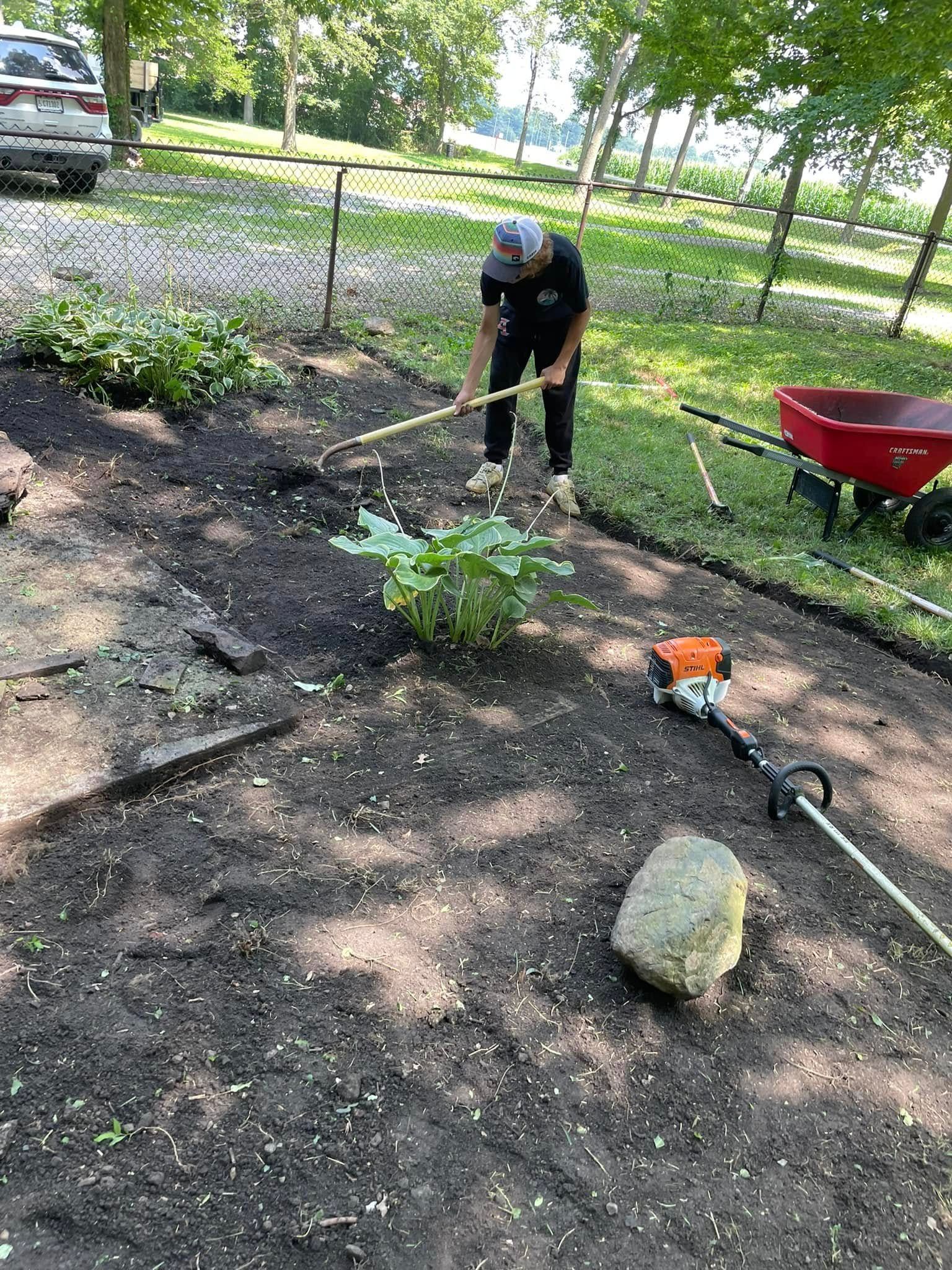 A man is raking the soil in a garden.