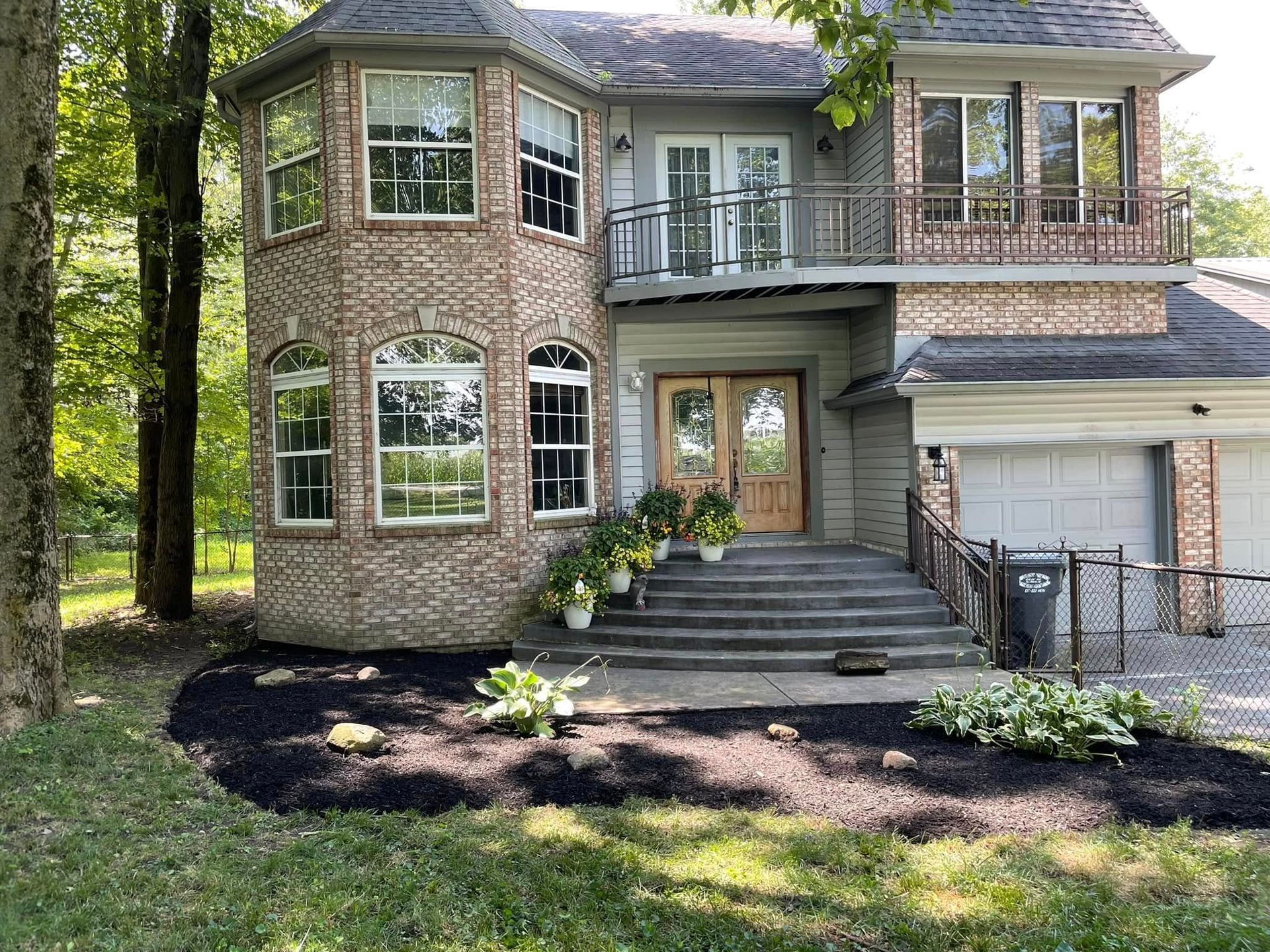 A large house with a lot of windows and stairs is surrounded by trees.