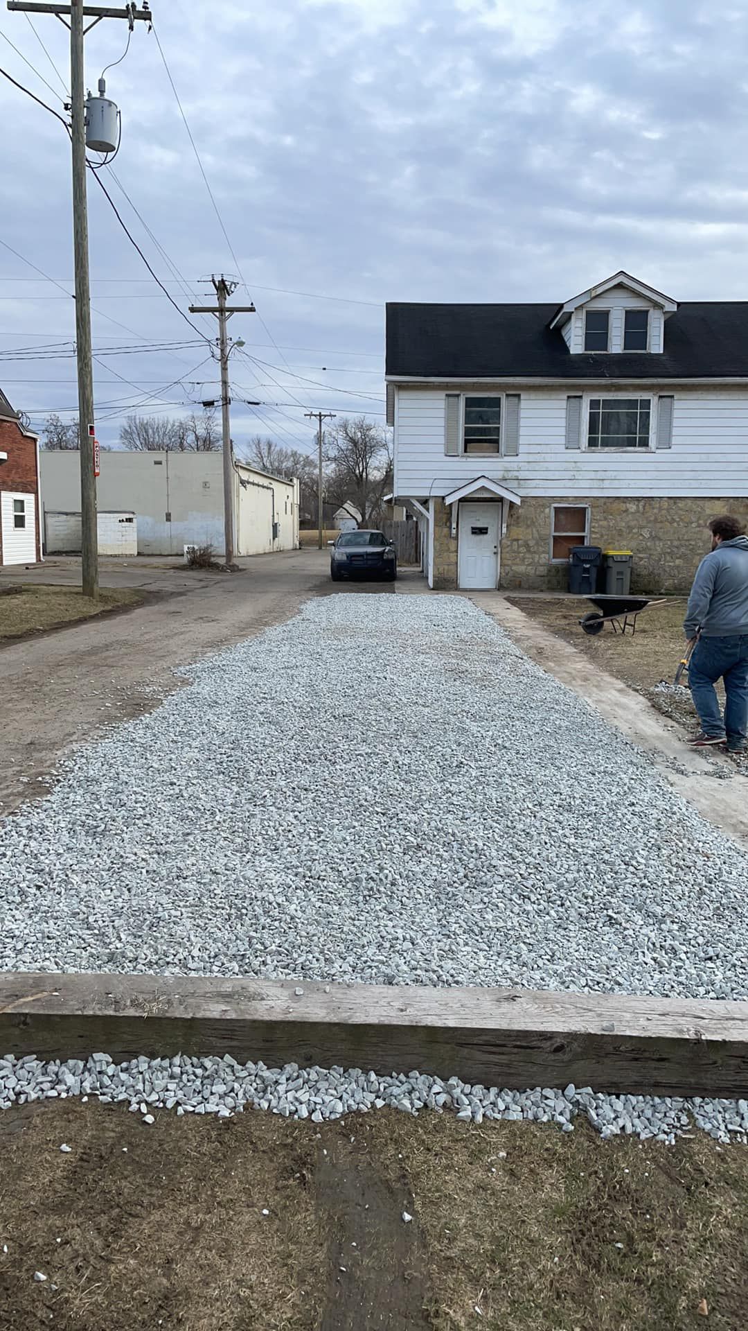 A gravel driveway is being built in front of a house.