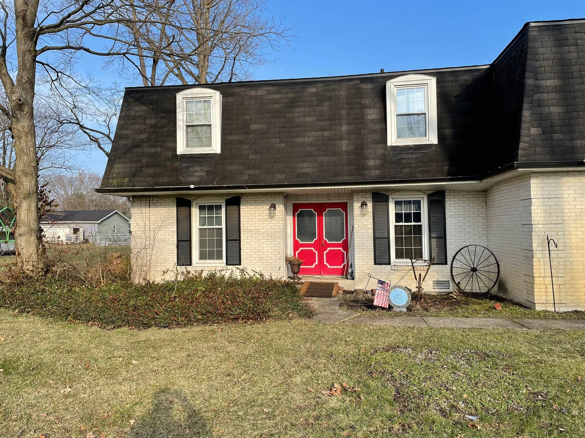 A white house with a red door and black shutters.