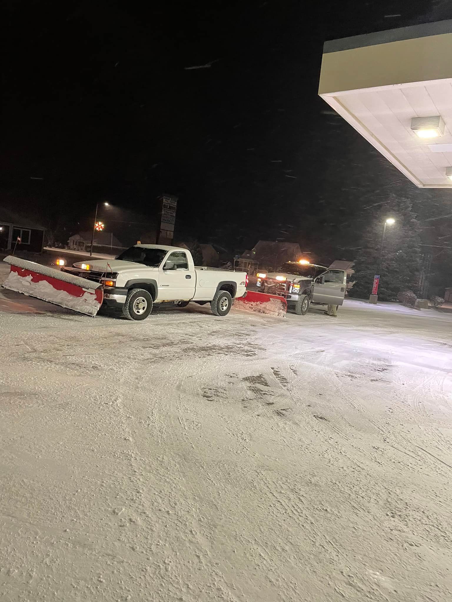 A white truck is parked in a snowy parking lot at night.