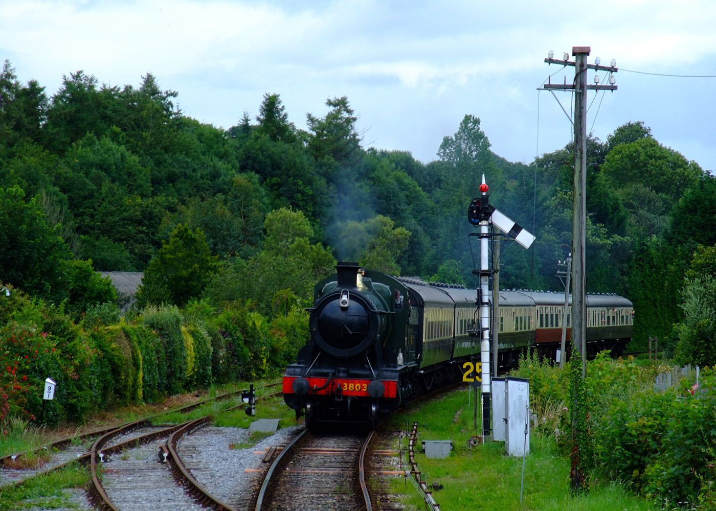 A train is going down train tracks in the countryside.
