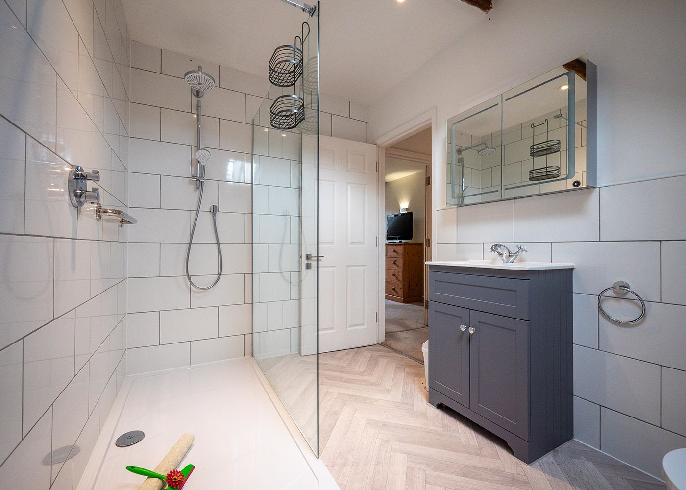 A bathroom with a walk in shower , sink and mirror.