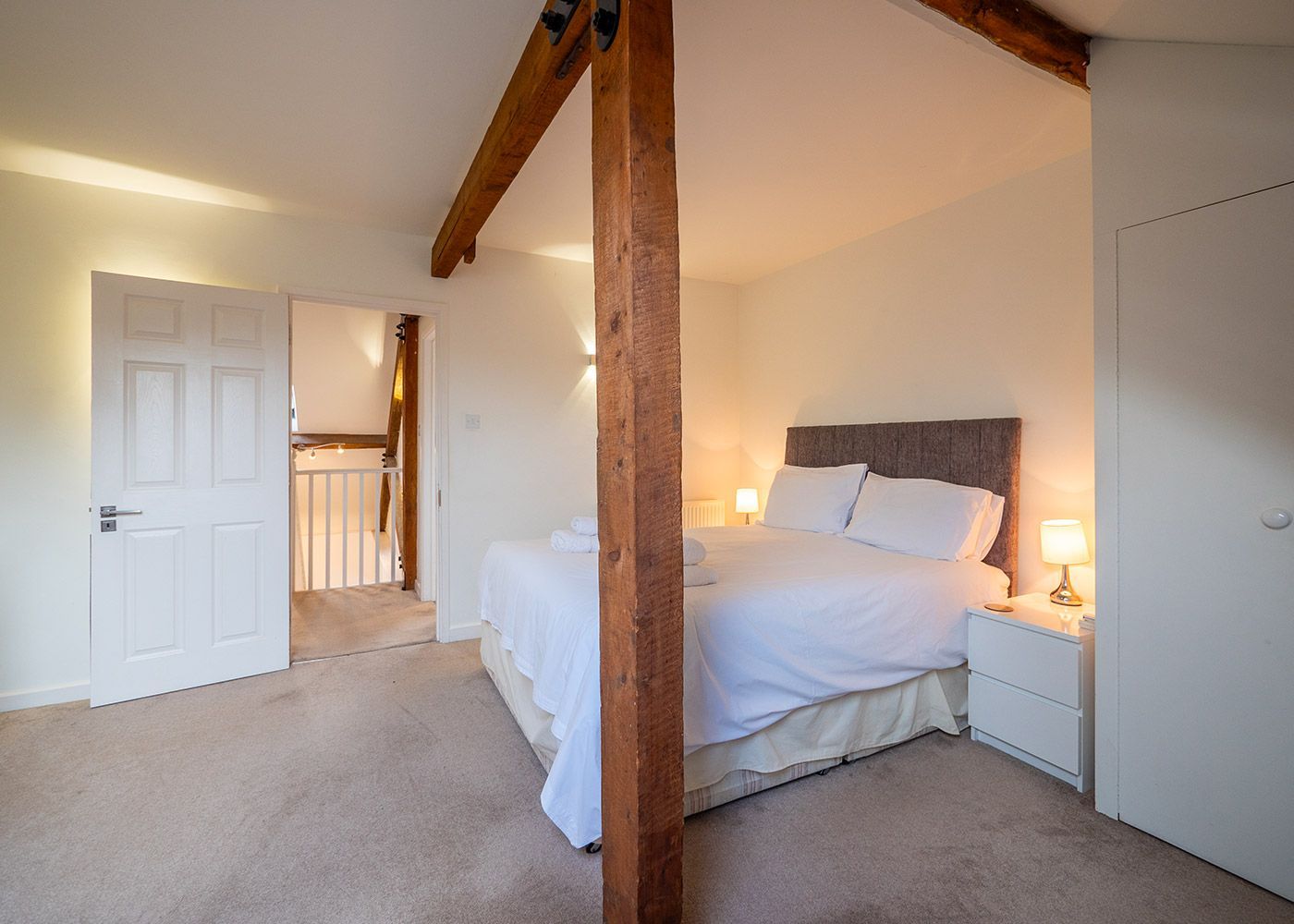 A bedroom with a king size bed , nightstands , and a staircase.