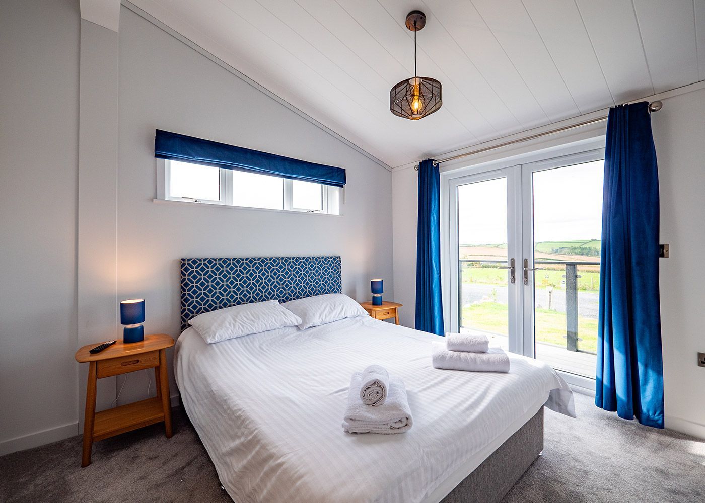 A bedroom with a king size bed and blue curtains.