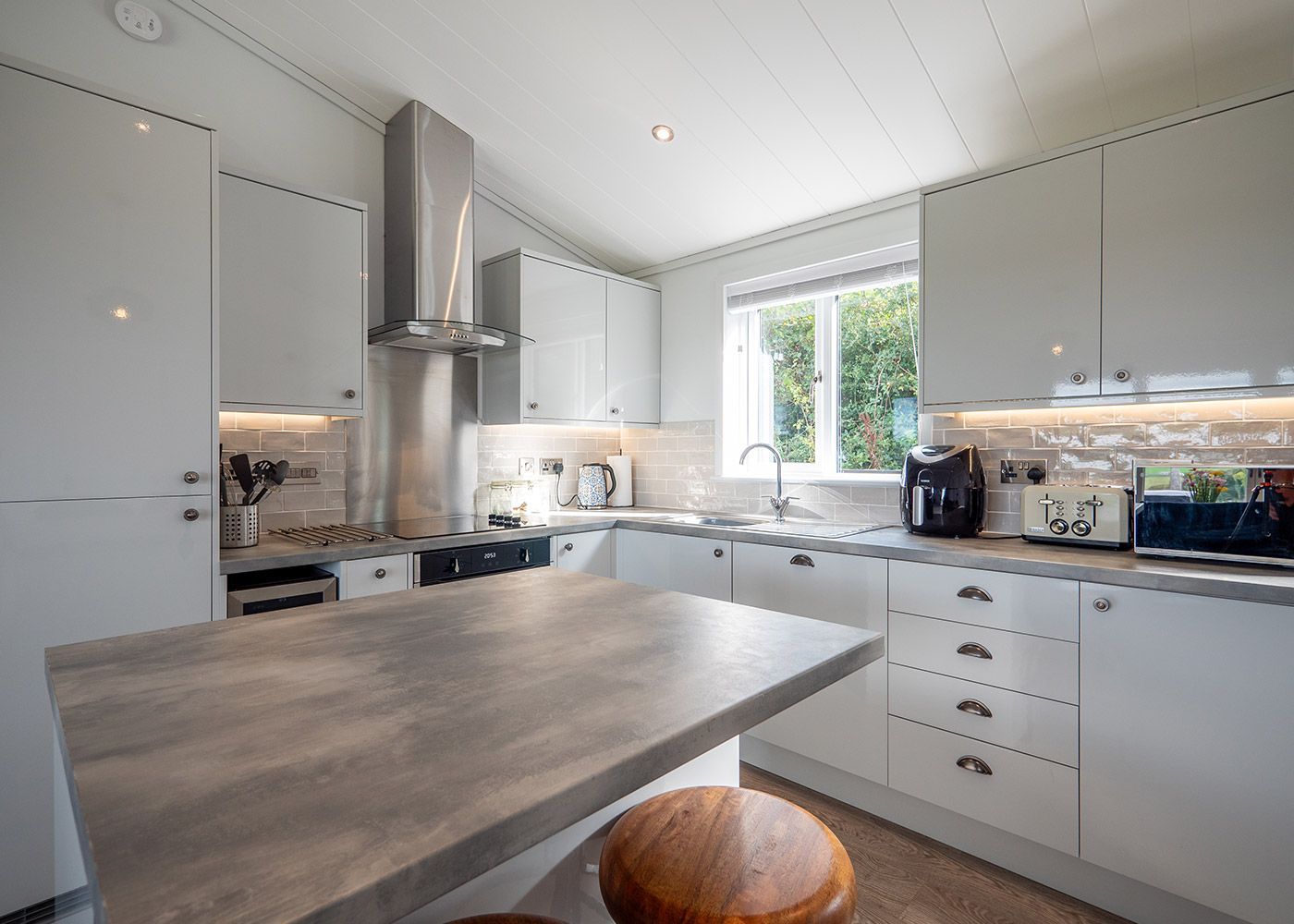 A kitchen with white cabinets , stainless steel appliances , a table and a window.