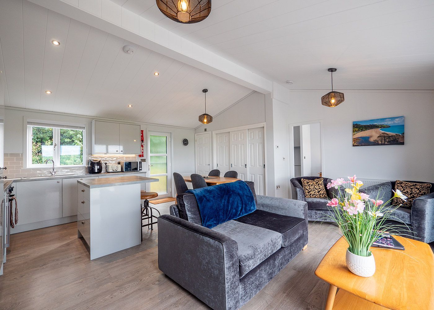 A living room with a couch , chairs , a table and a vase of flowers.
