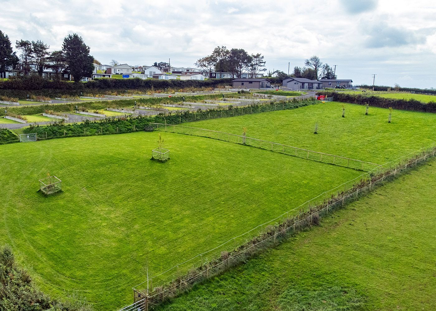 An aerial view of a lush green field with a fence surrounding it.