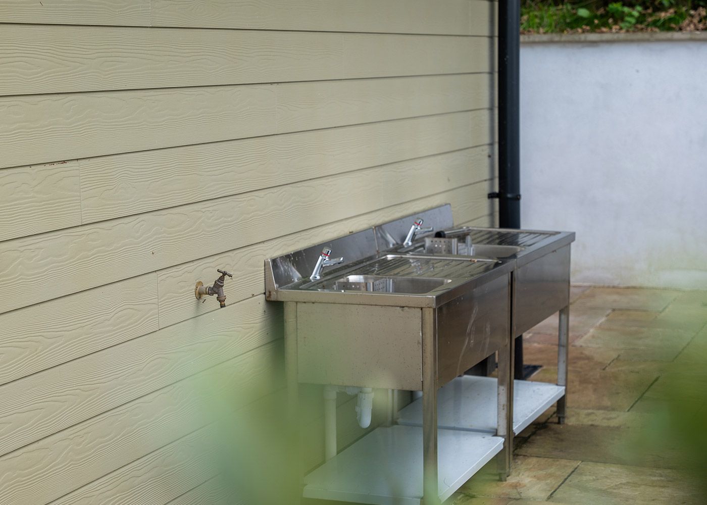 Two stainless steel sinks are sitting outside of a building.