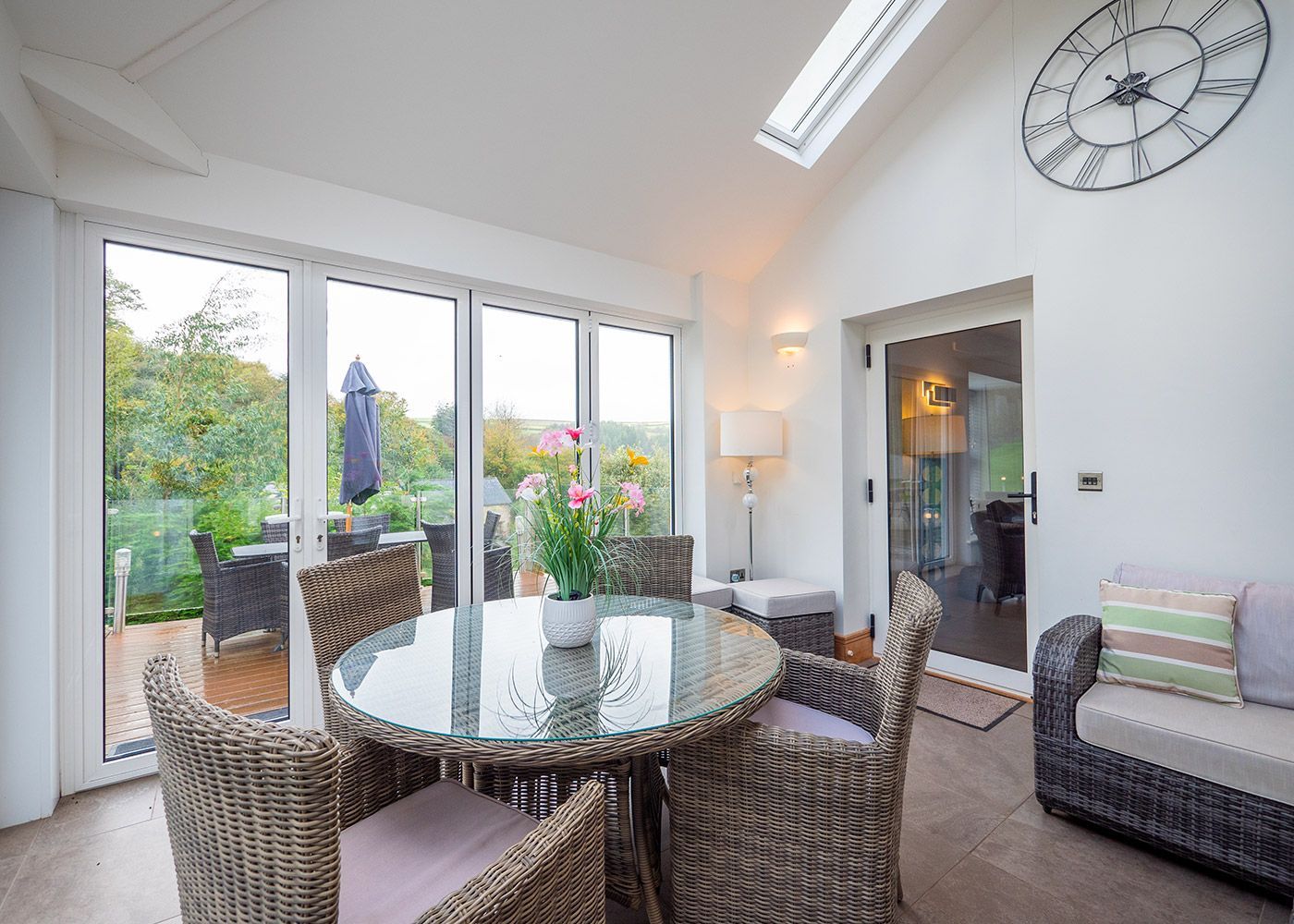 A living room with a table and chairs and a clock on the wall.